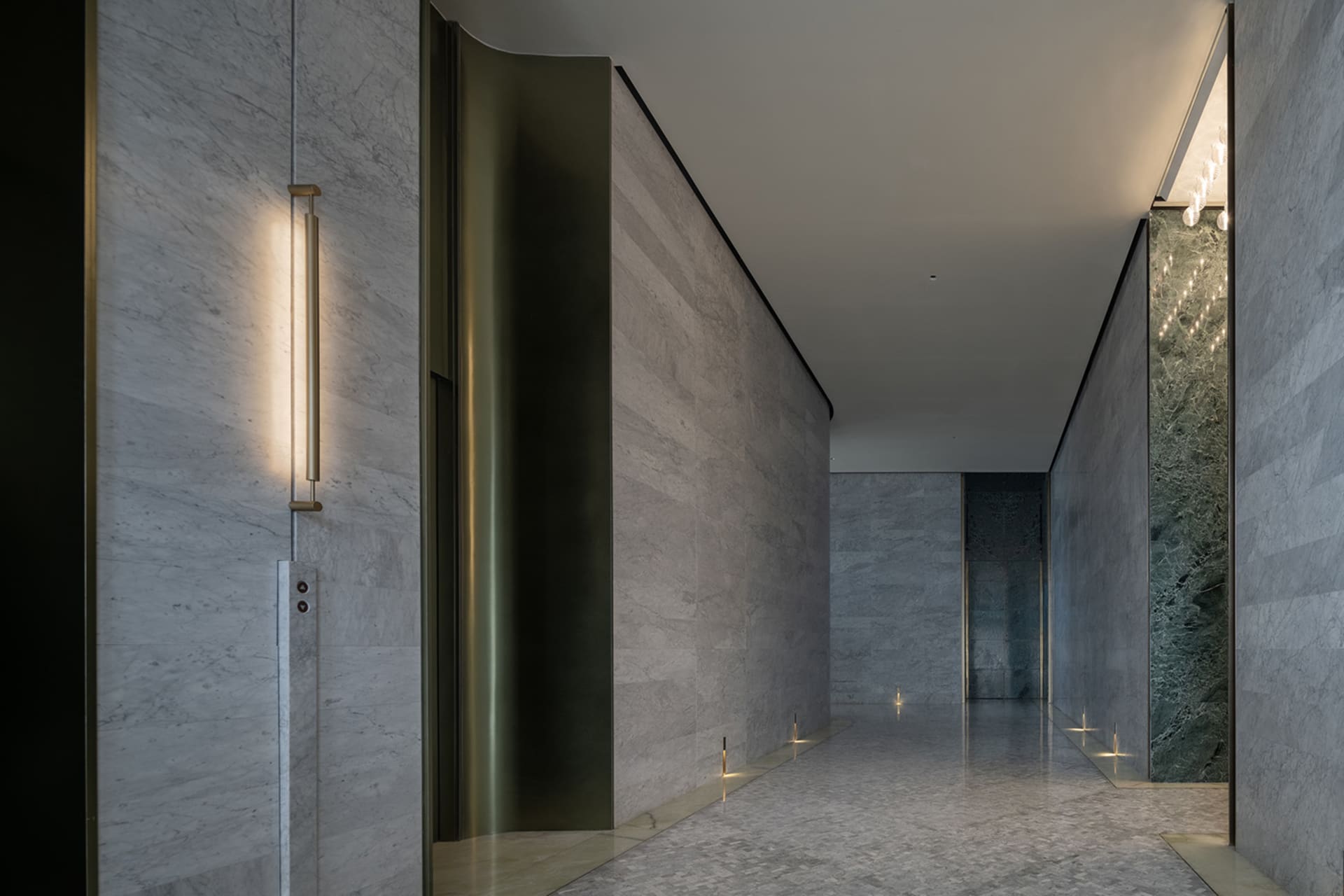 A modern marble corridor with integrated lighting on the walls and floor.