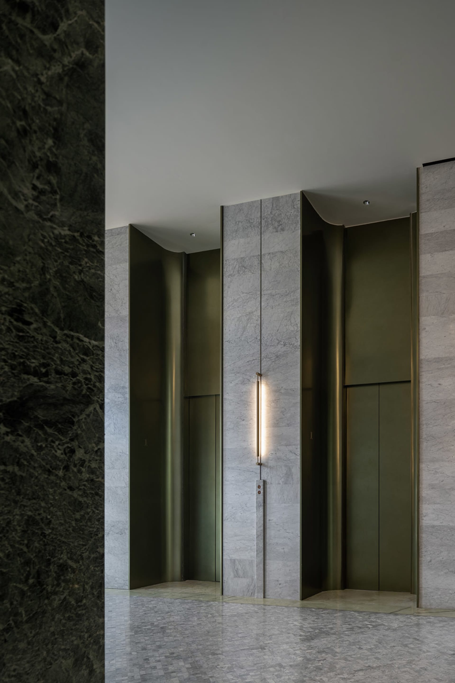 Modern lobby entrance featuring marble walls and vertical lighting fixture