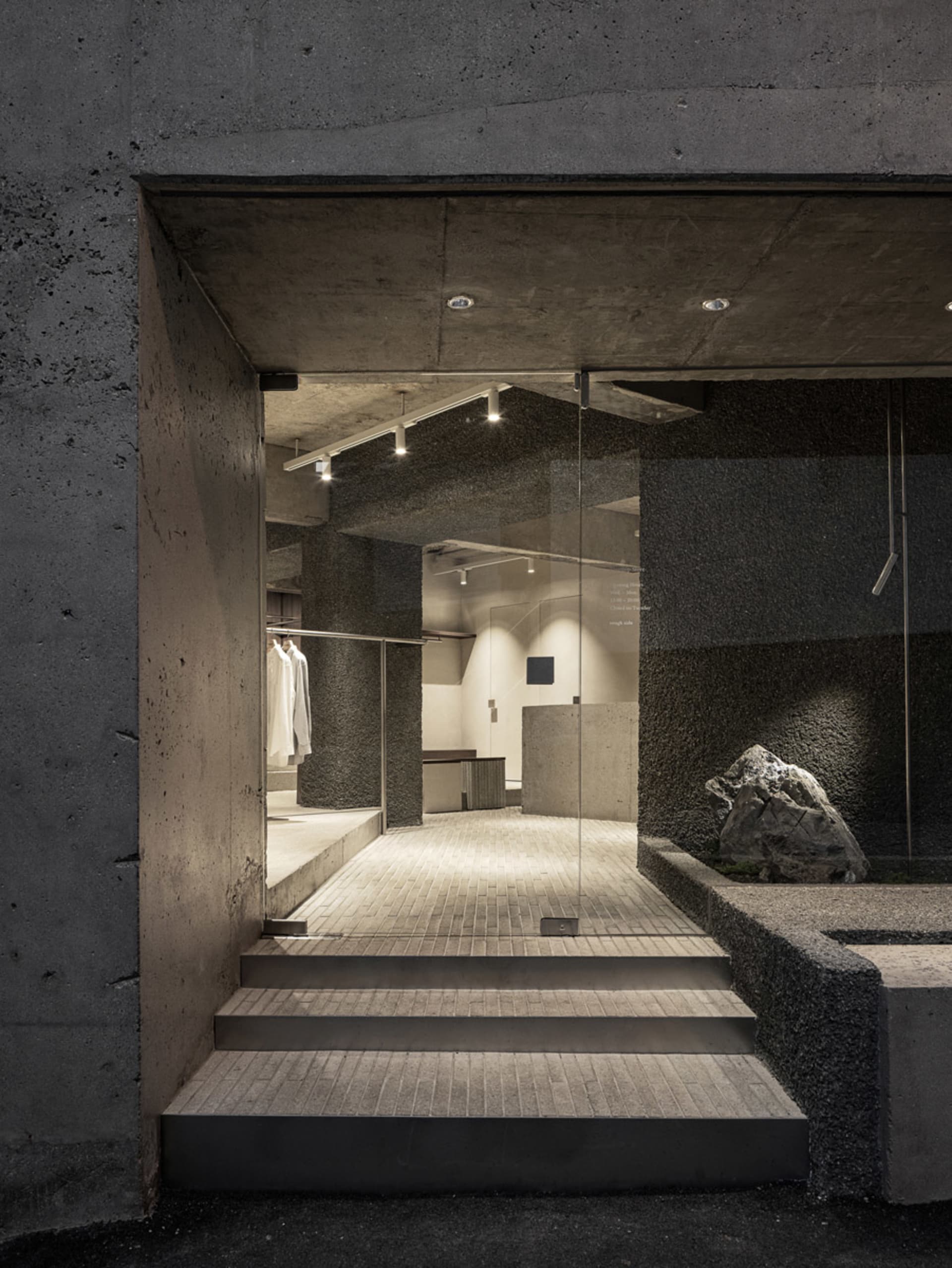 Minimalist industrial retail storefront with concrete and glass materials.