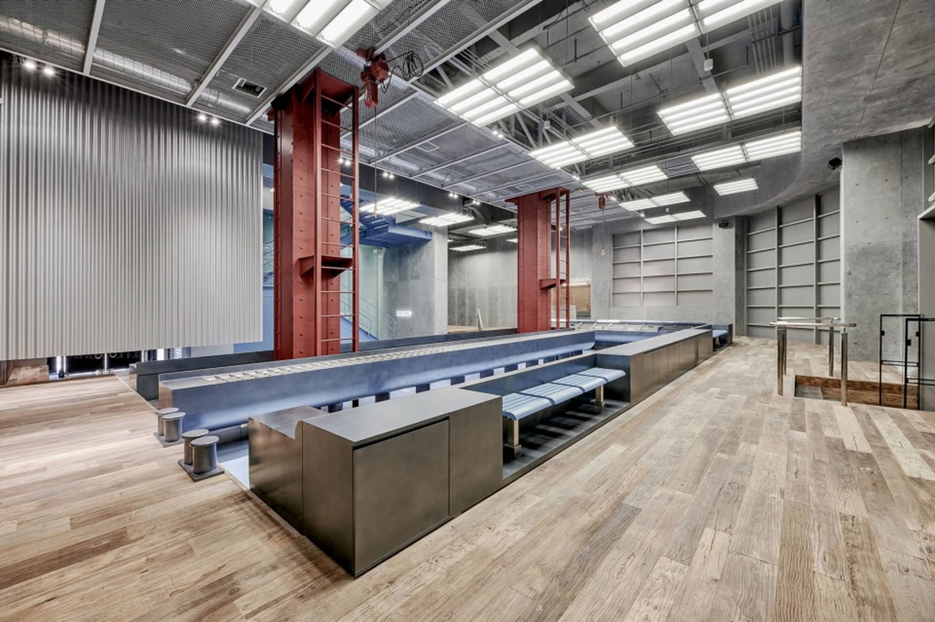 A spacious workshop featuring industrial design elements, such as metal and concrete structures, and a metallic conveyor syst