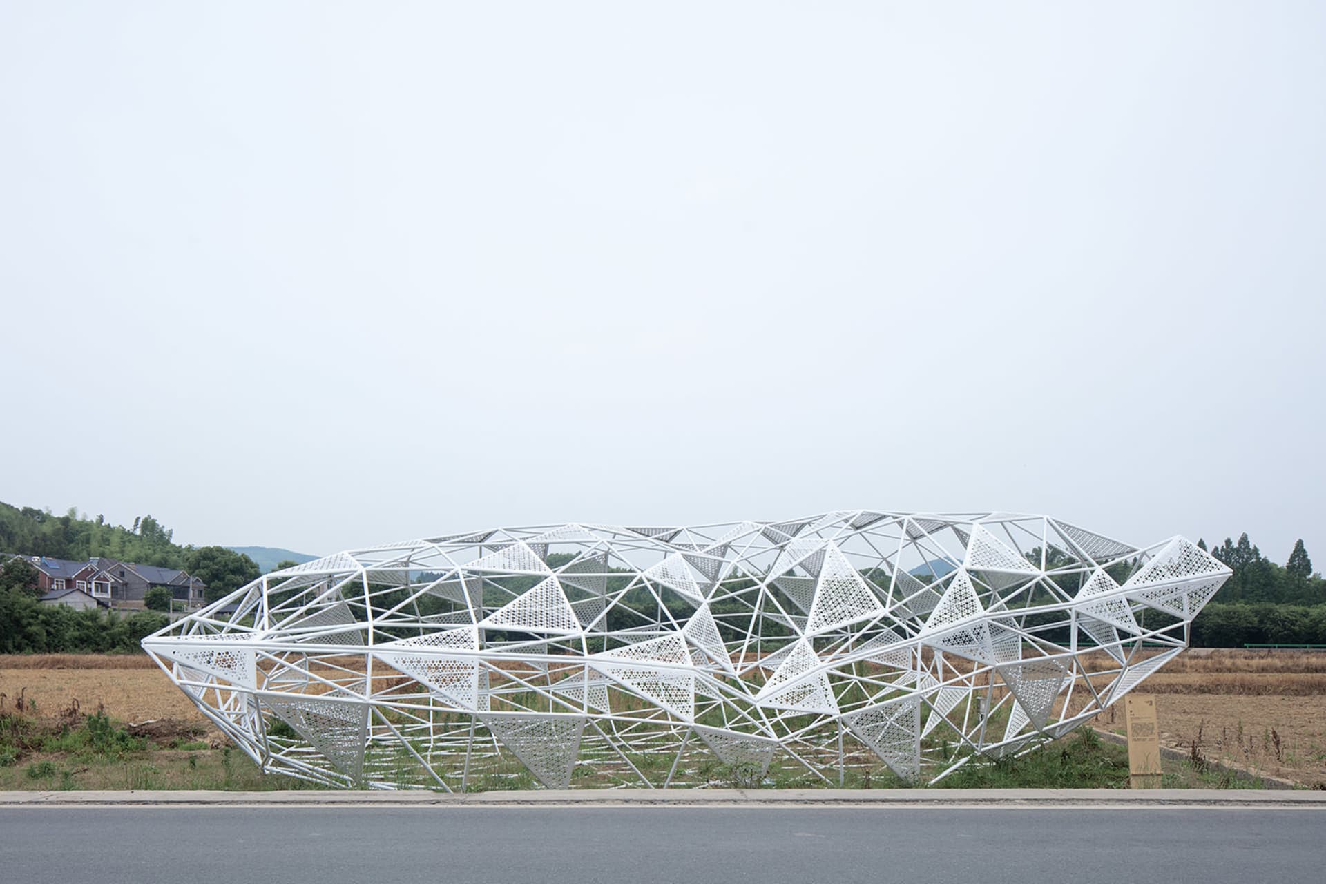 A modern, white metal frame structure in an open field.