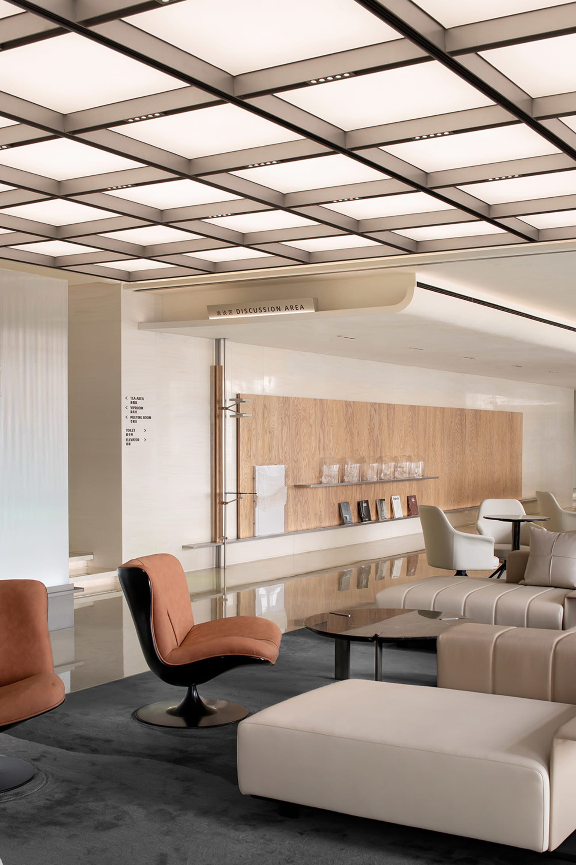 A modern discussion area with minimalist furniture, wooden panels, and a sleek, reflective floor.