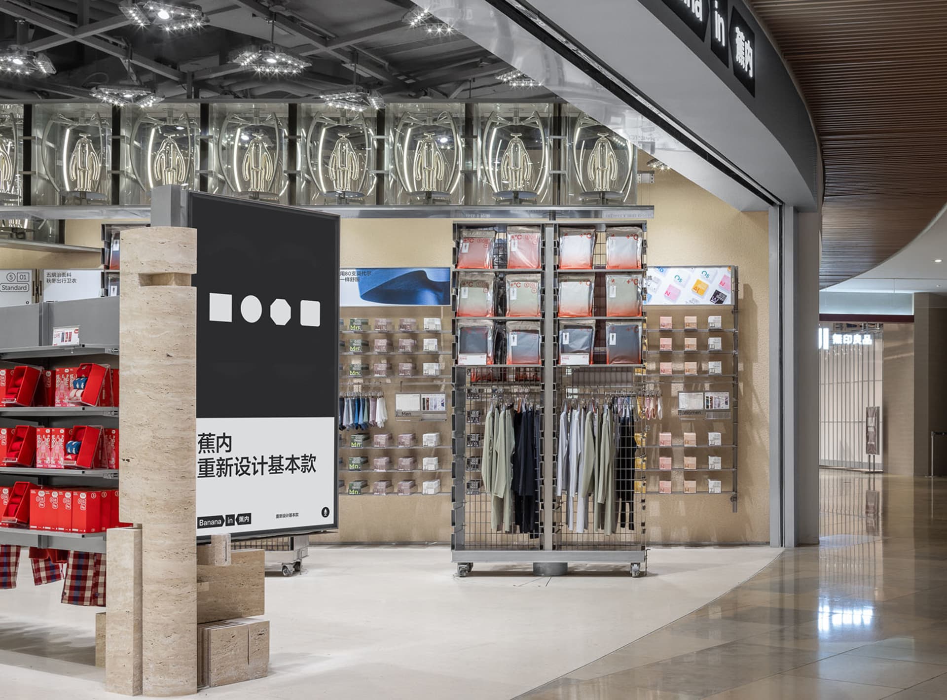 Retail store displaying clothing on metallic racks and hanging Rails with glass and concrete accents.