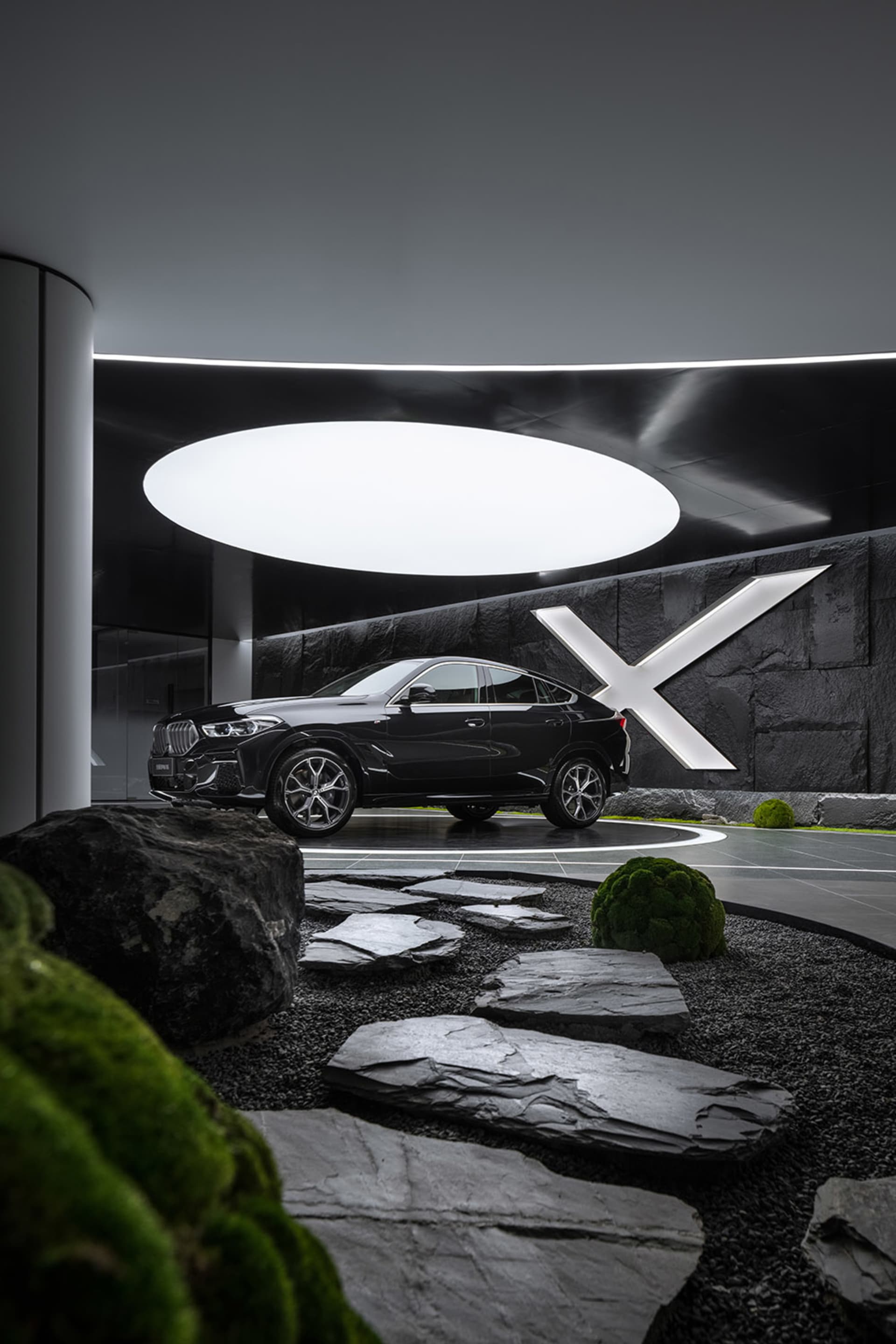 Modern car dealership interior with black metal accents and a sleek black car on display.