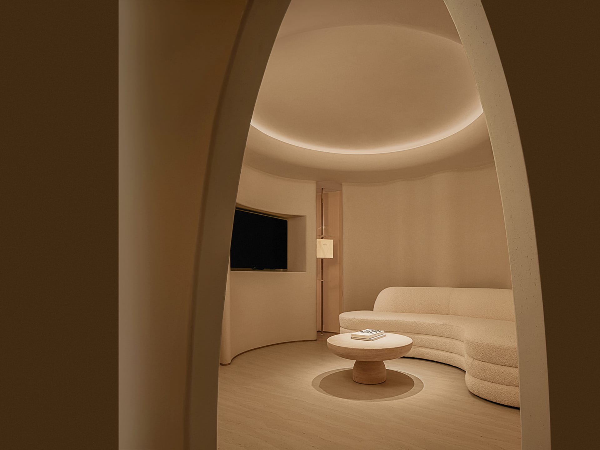 A minimalist living room with a curved sofa in textured cloth and a round coffee table.