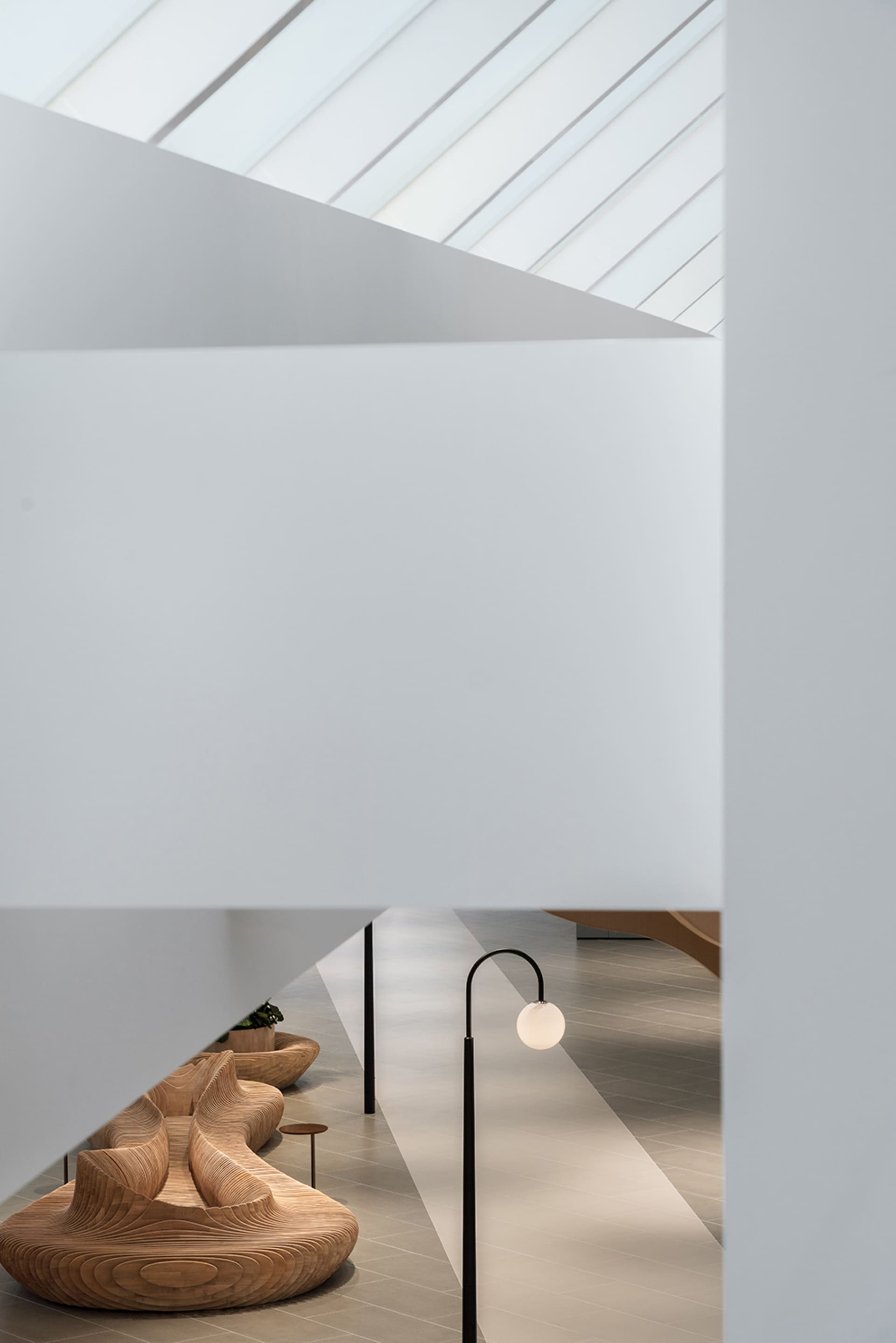 A modern office interior featuring wooden benches and glass railings.