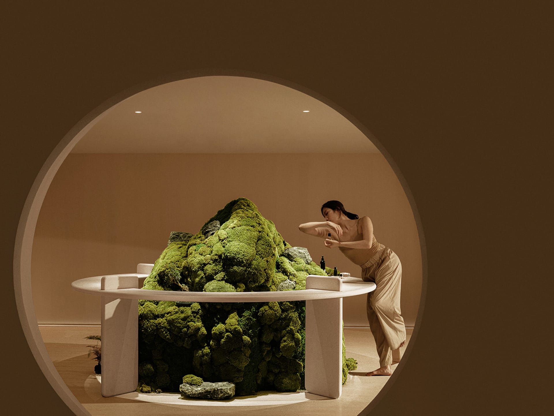 A spa interior with a moss-covered table and a woman leaning over it.