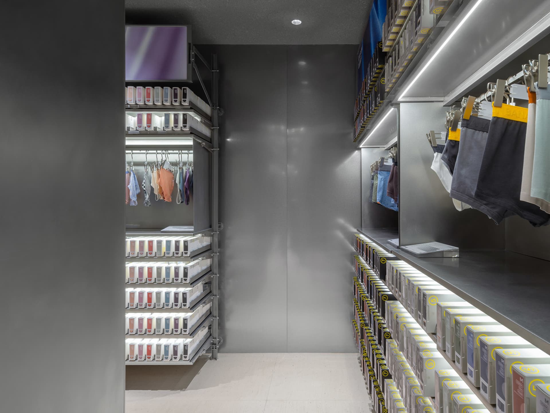 一間現代零售店,展示金屬層架系統的服裝衣櫃。
