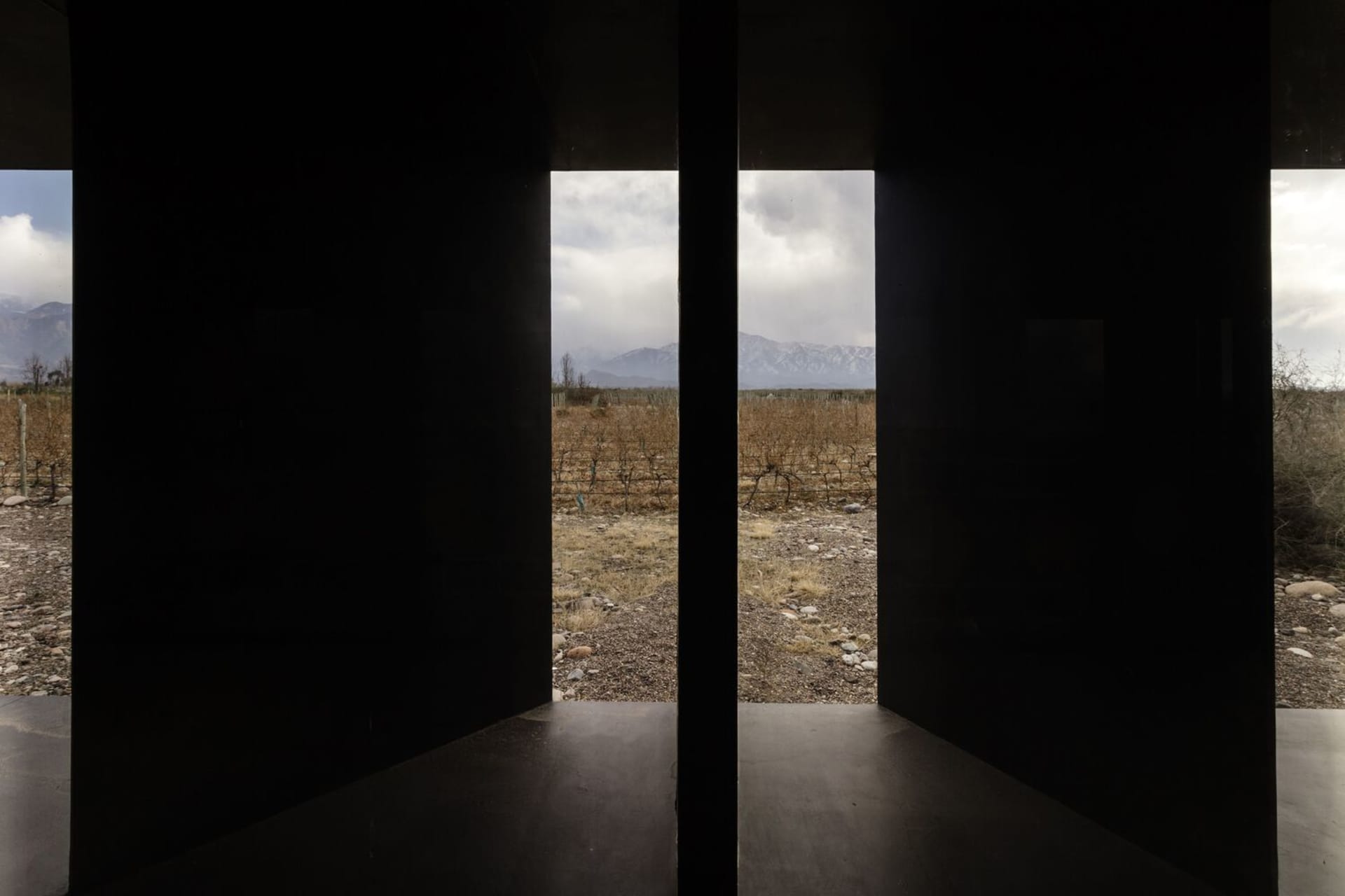 A view through glass panels of a landscape with mountains in the distance and a cloudy sky.