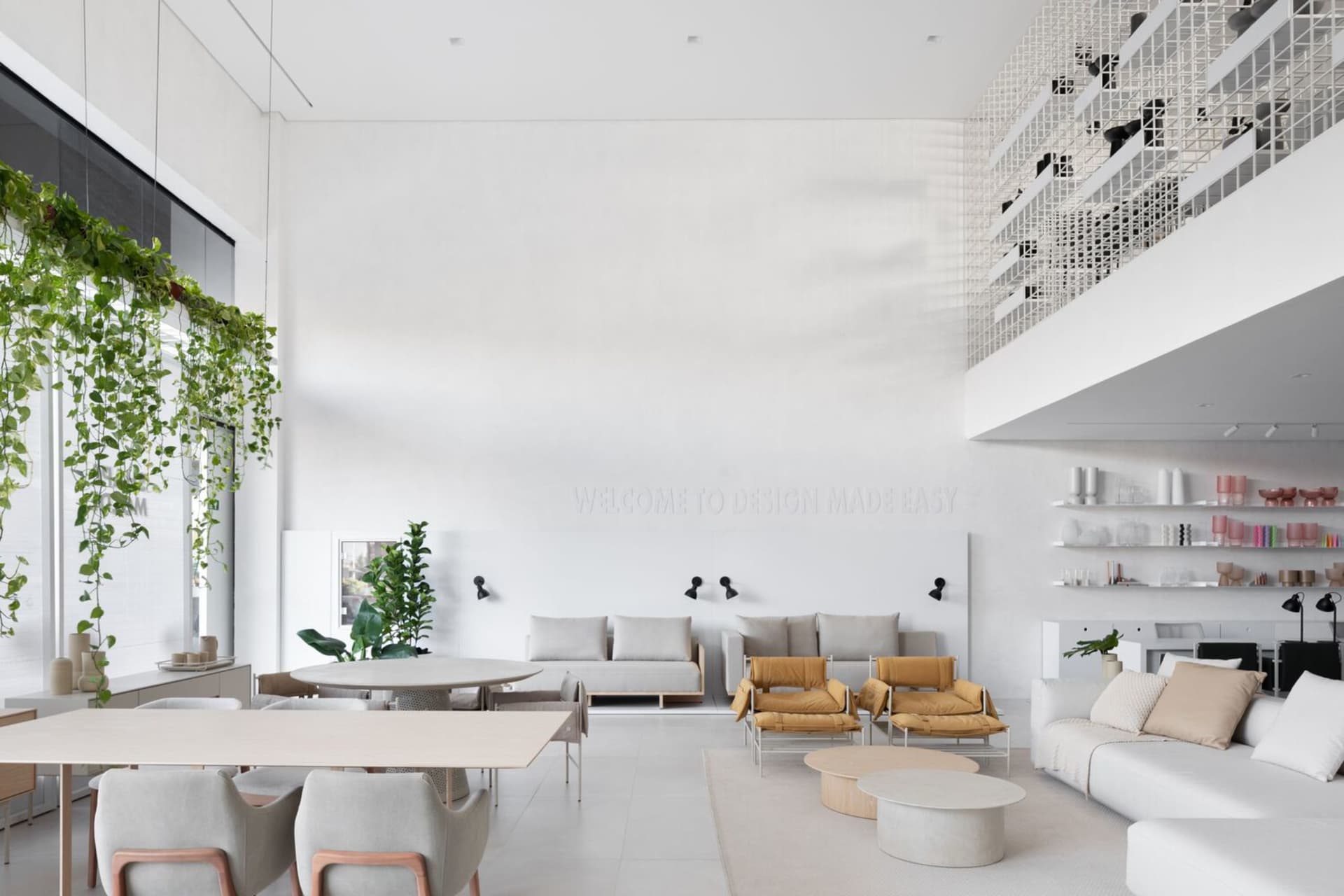 A modern minimalist living room with white walls, furniture, and green plants.