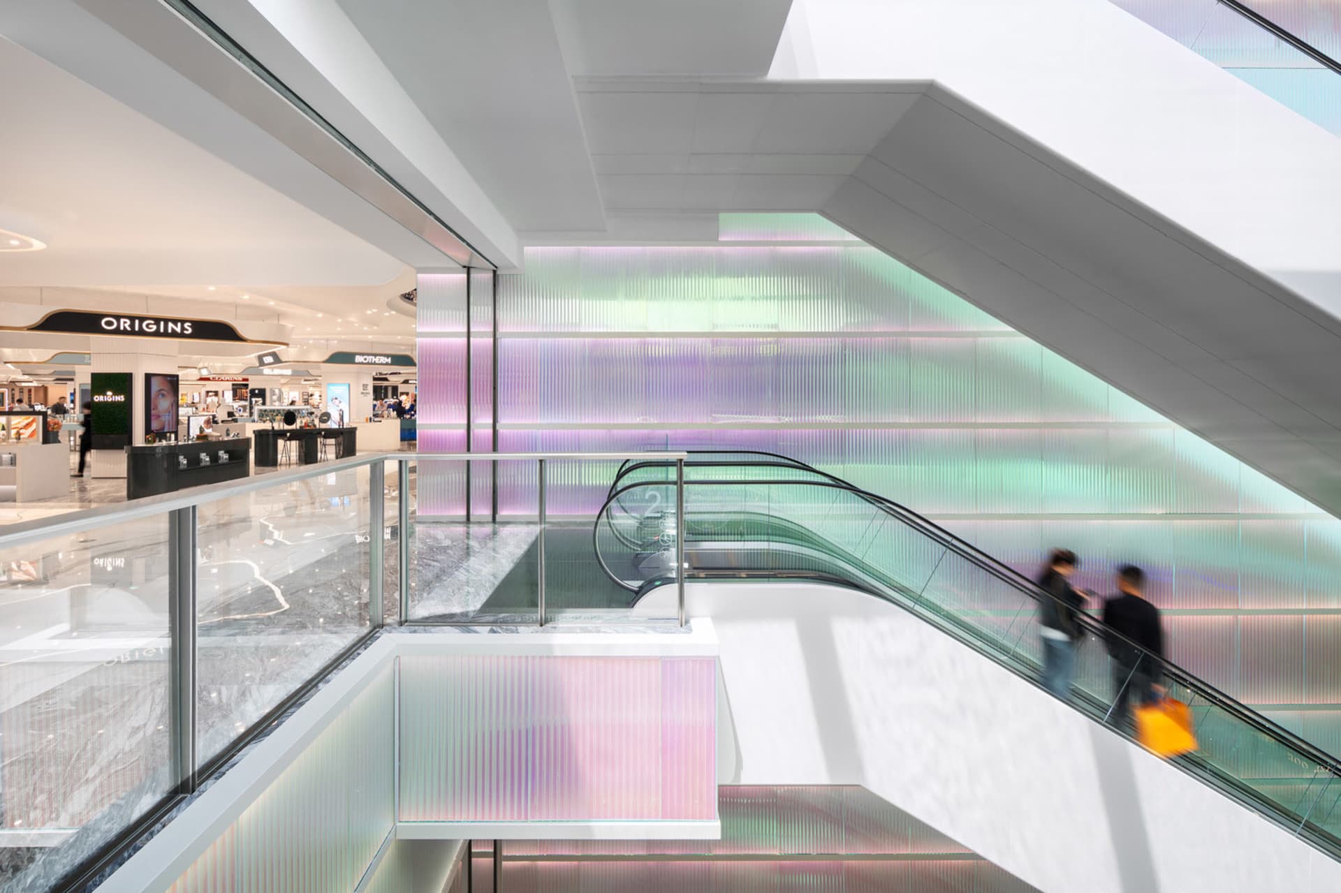 Modern shopping mall interior with glass walls and colorful flower installations.
