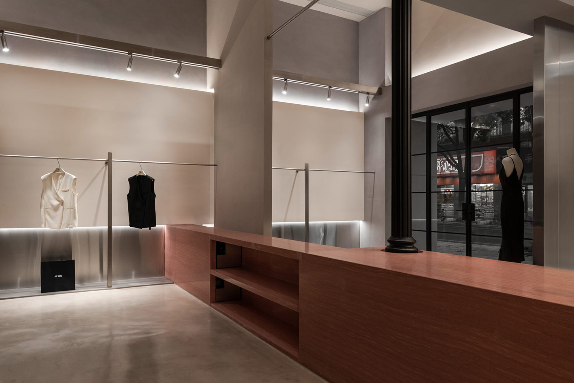Modern retail store interior with clothing racks made of metal, glass, and wooden panels.