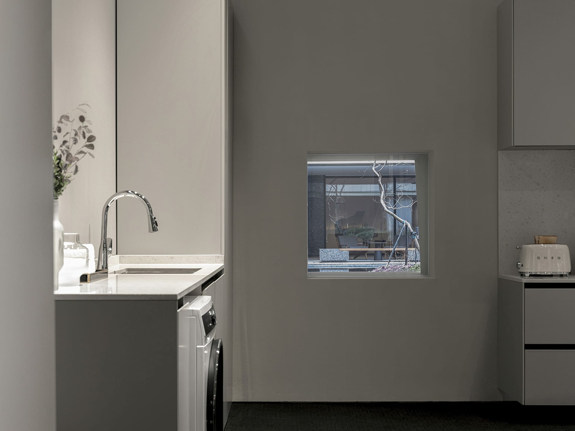 Modern kitchen with marble countertop and sink, featuring a window looking out to a pool and outdoor seating area.