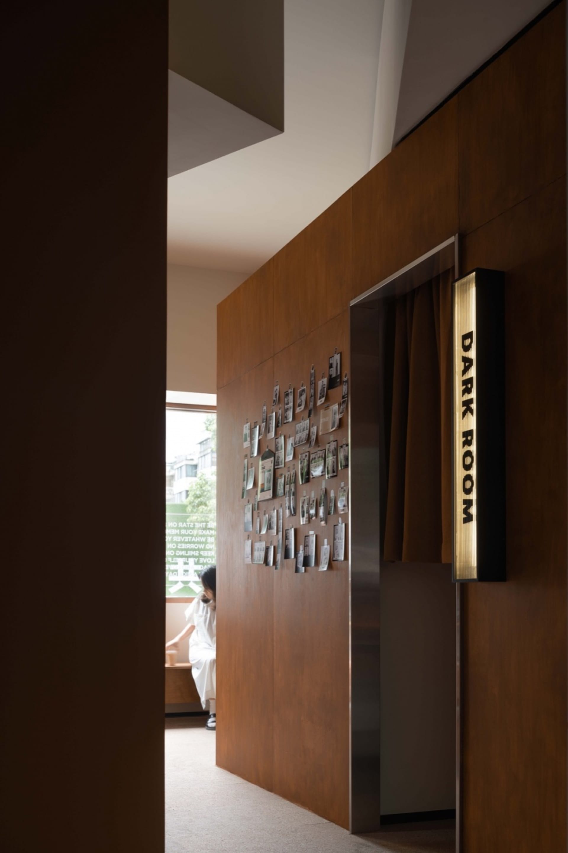 A dark room with wooden paneled walls featuring a collection of framed photographs on the left wall.