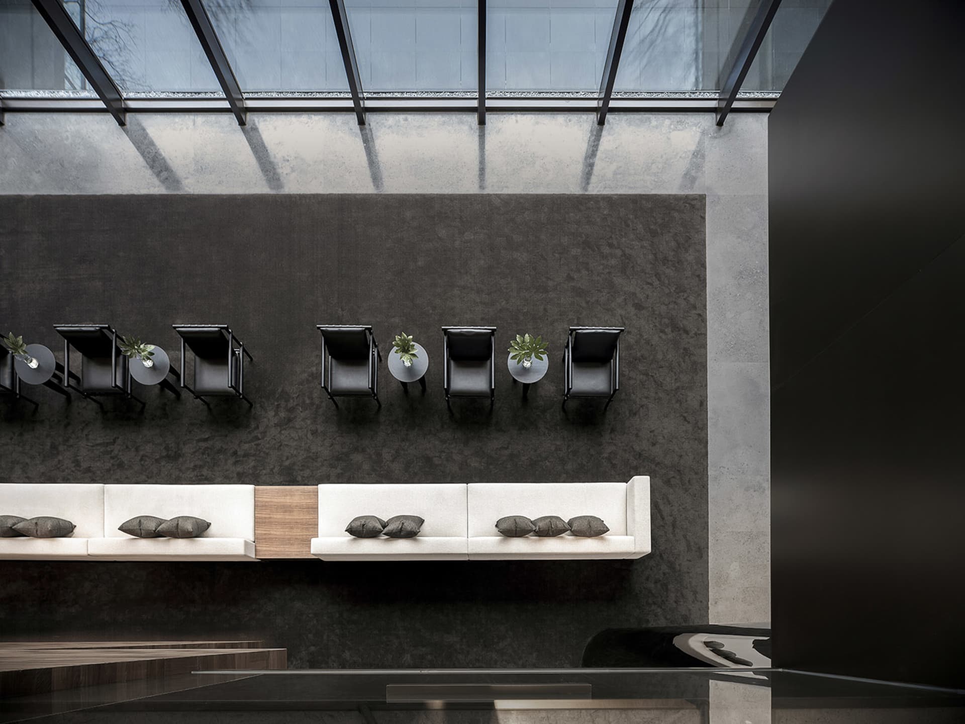 Modern office lounge area with concrete walls and glass partitions.