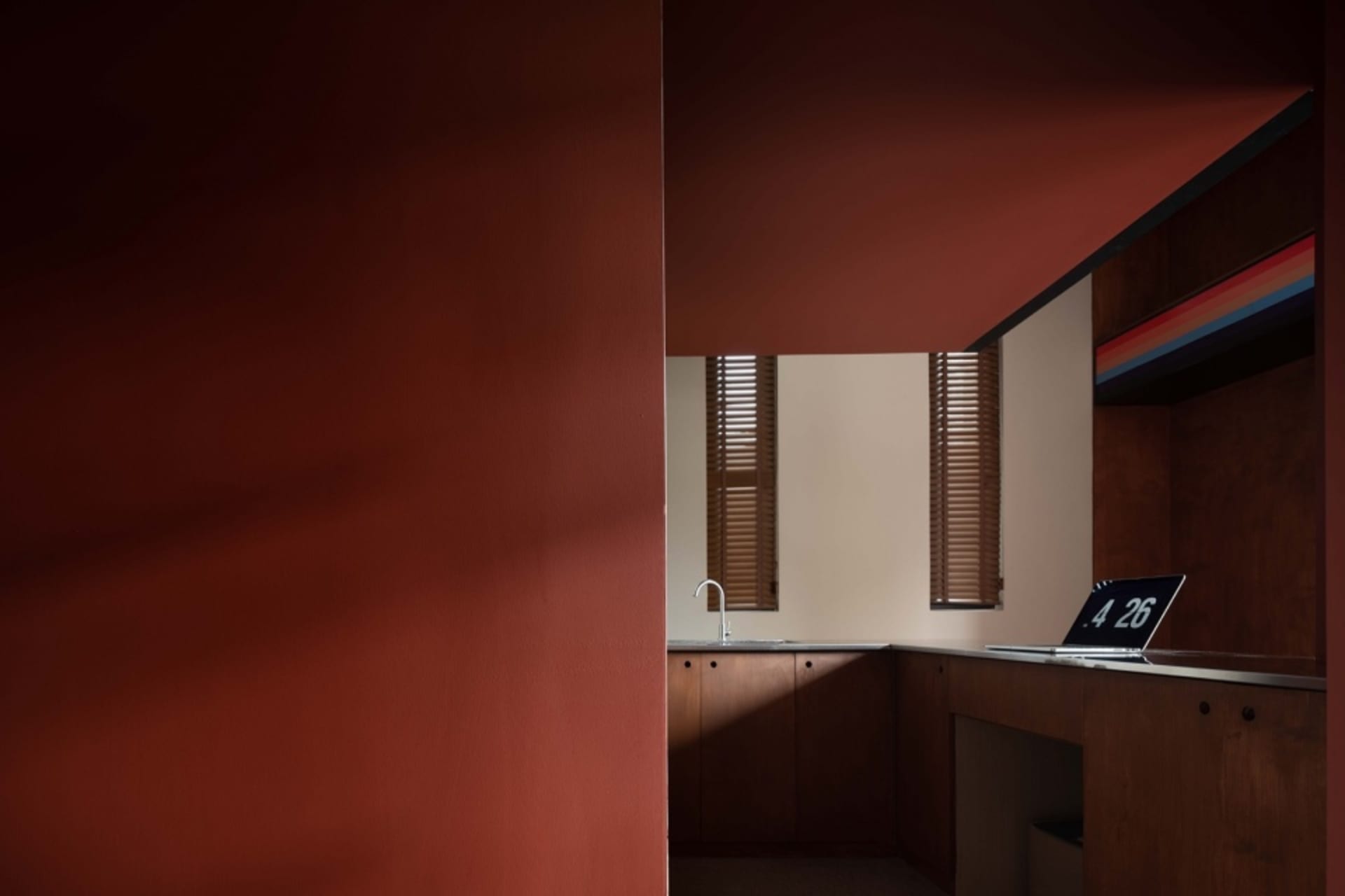 An interior office space featuring minimalist design with wooden cabinets and a laptop on a desk.