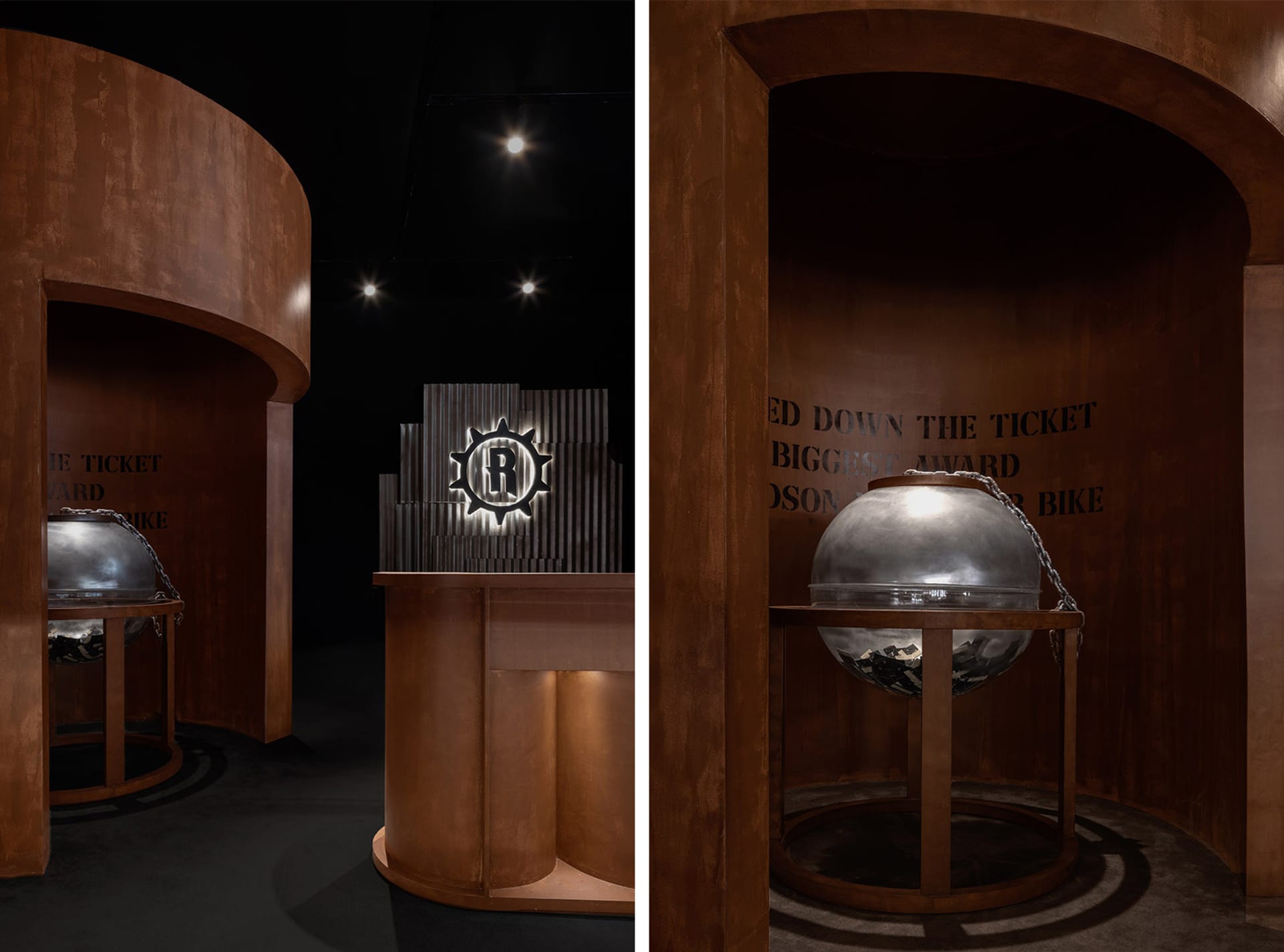 A metal sphere with a textured surface and chain links on a wooden stand in an industrial-themed exhibit environment.