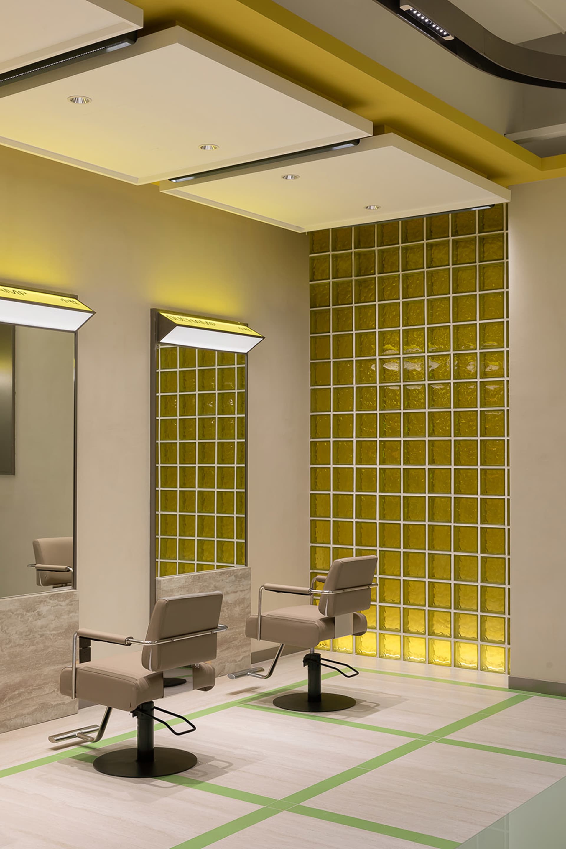 Modern interior design of a hair salon featuring glass tiles and leather chairs.
