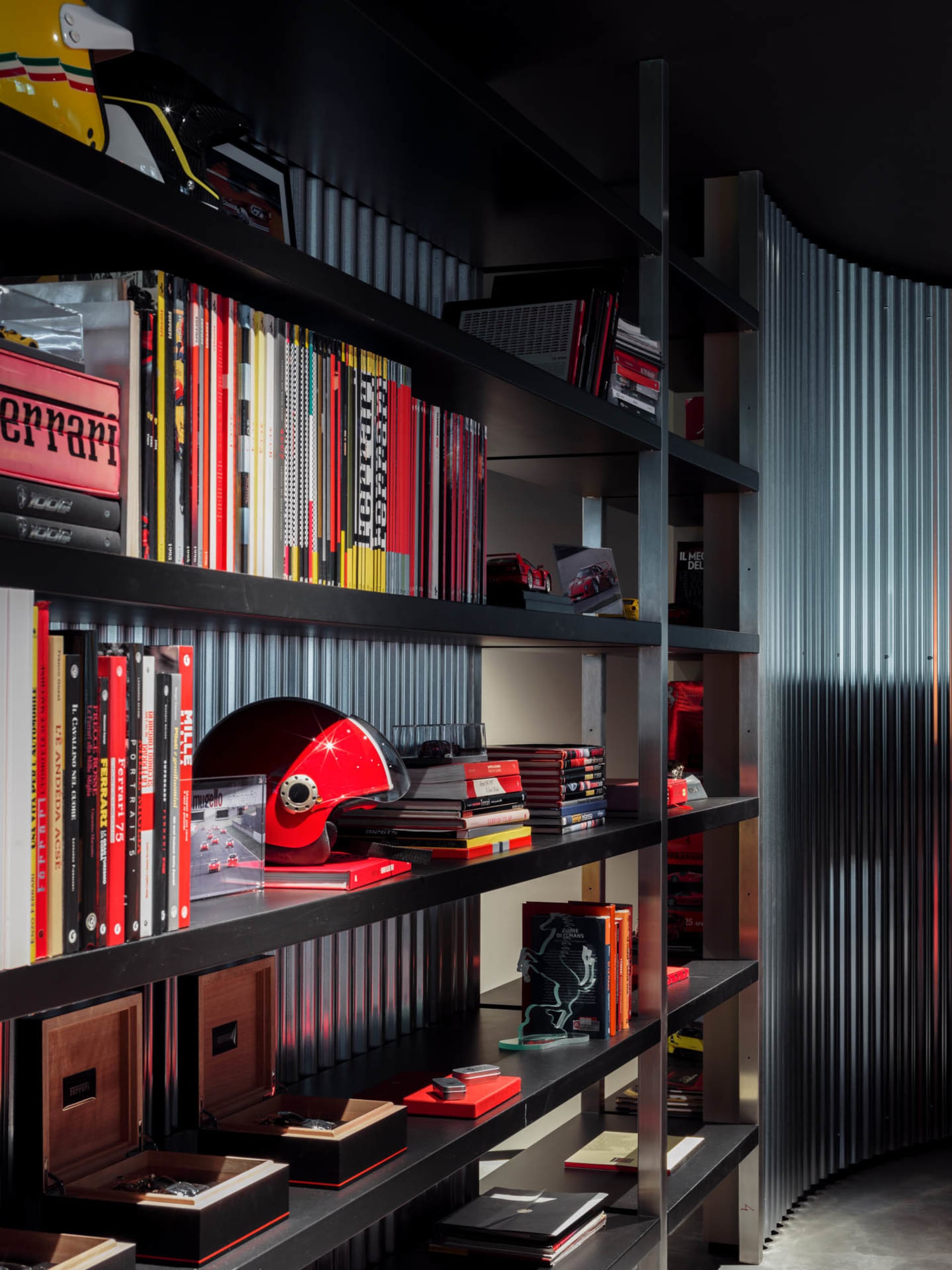 Modern home library with black metal shelves filled with books and racing helmets.