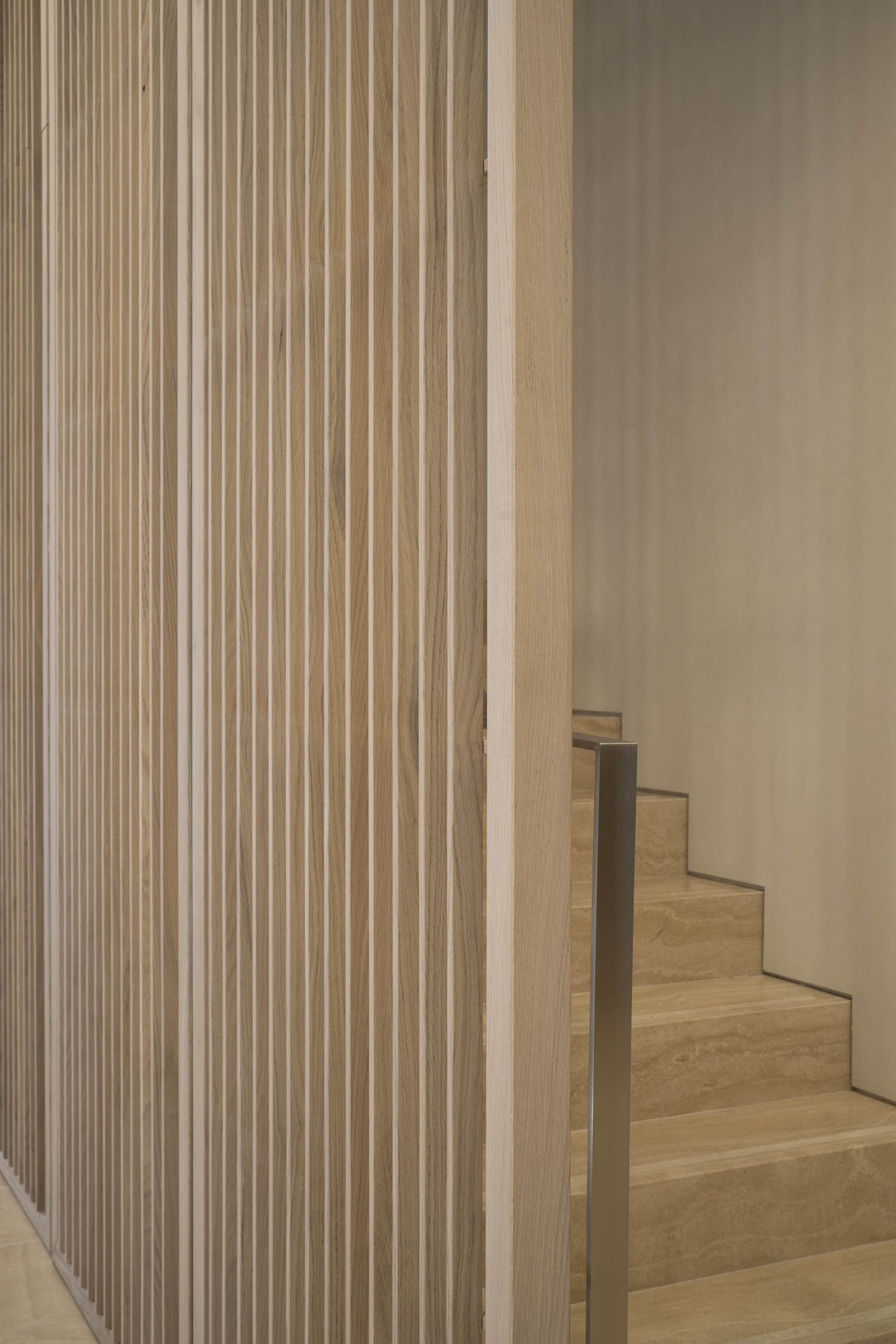 Modern minimalist wooden staircase with vertical slats and metallic handrail