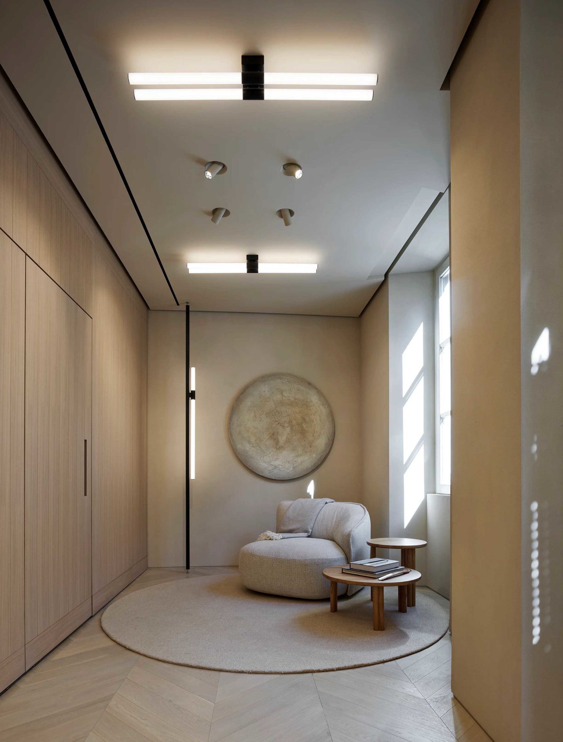 Modern minimalist living room with wooden walls, fabric seating, and a circular area rug.