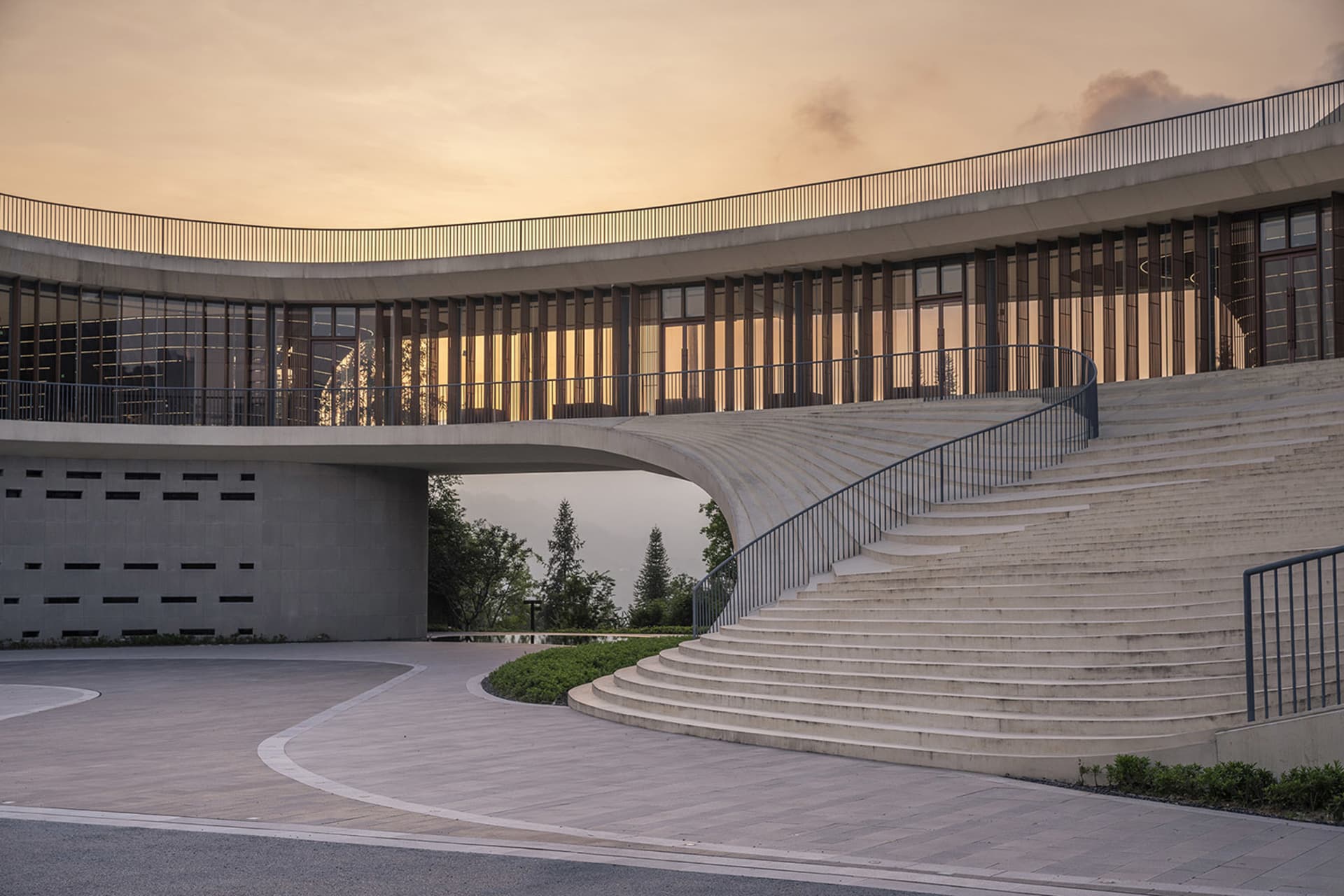 Modern building facade with concrete, glass, and wooden elements at dusk.