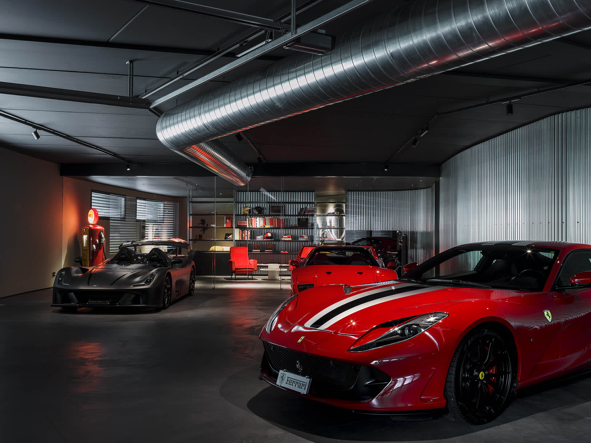 Well-lit car dealership with sleek metallic finishes, concrete flooring, and high glass elements