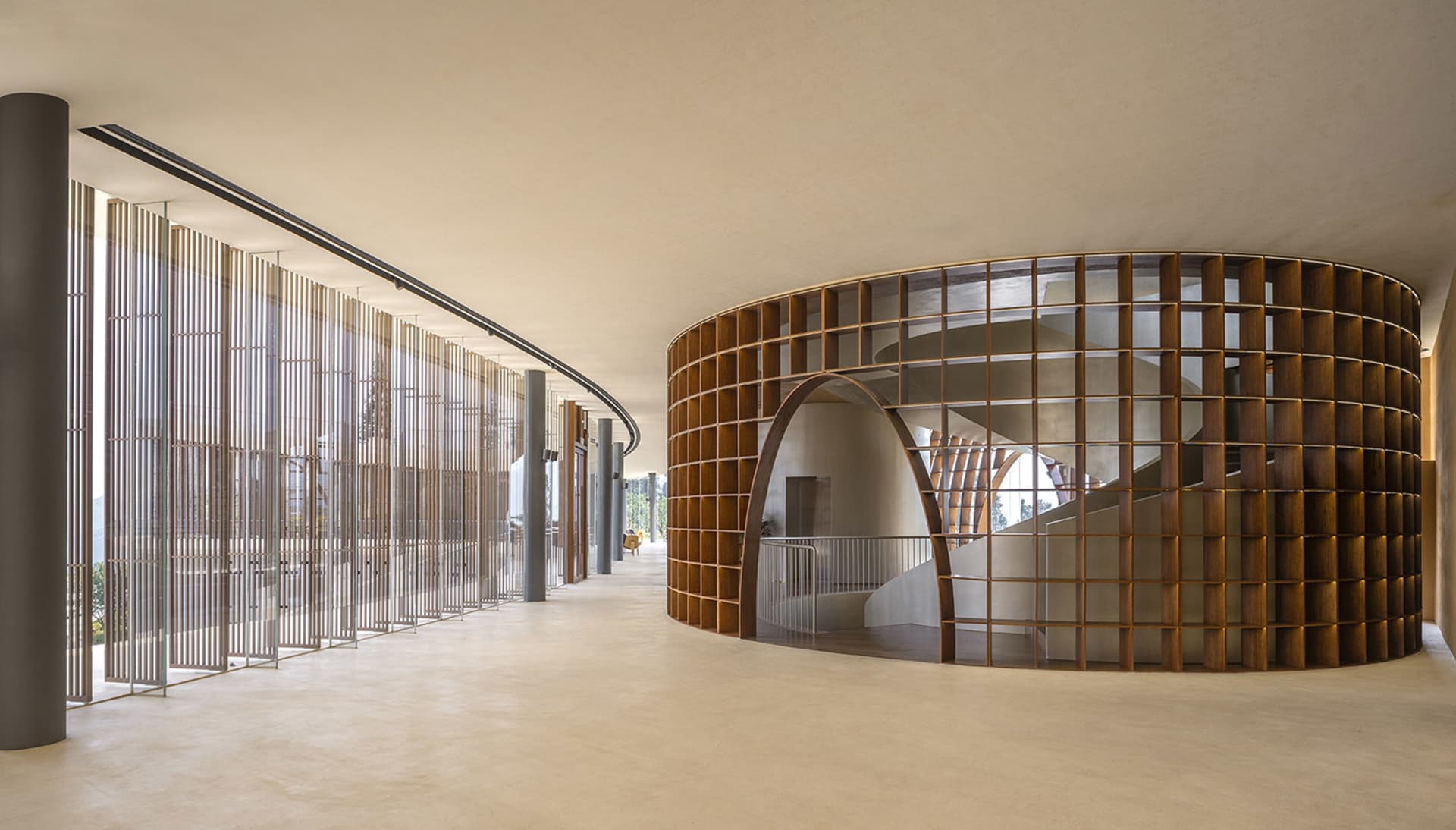 A modern interior space featuring a wooden spiral staircase with arches and a railing.