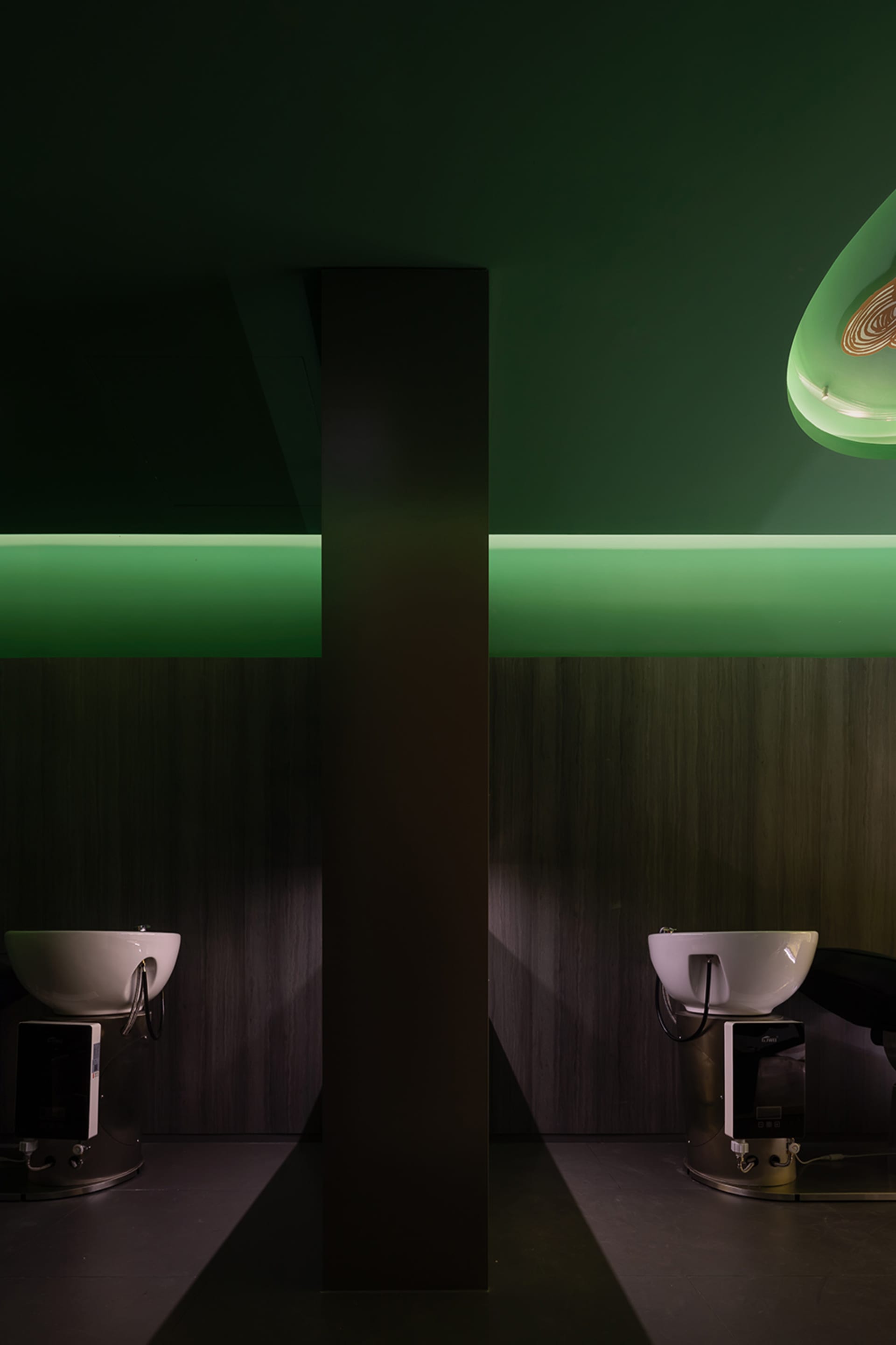 A modern salon interior with green accents and white sinks.