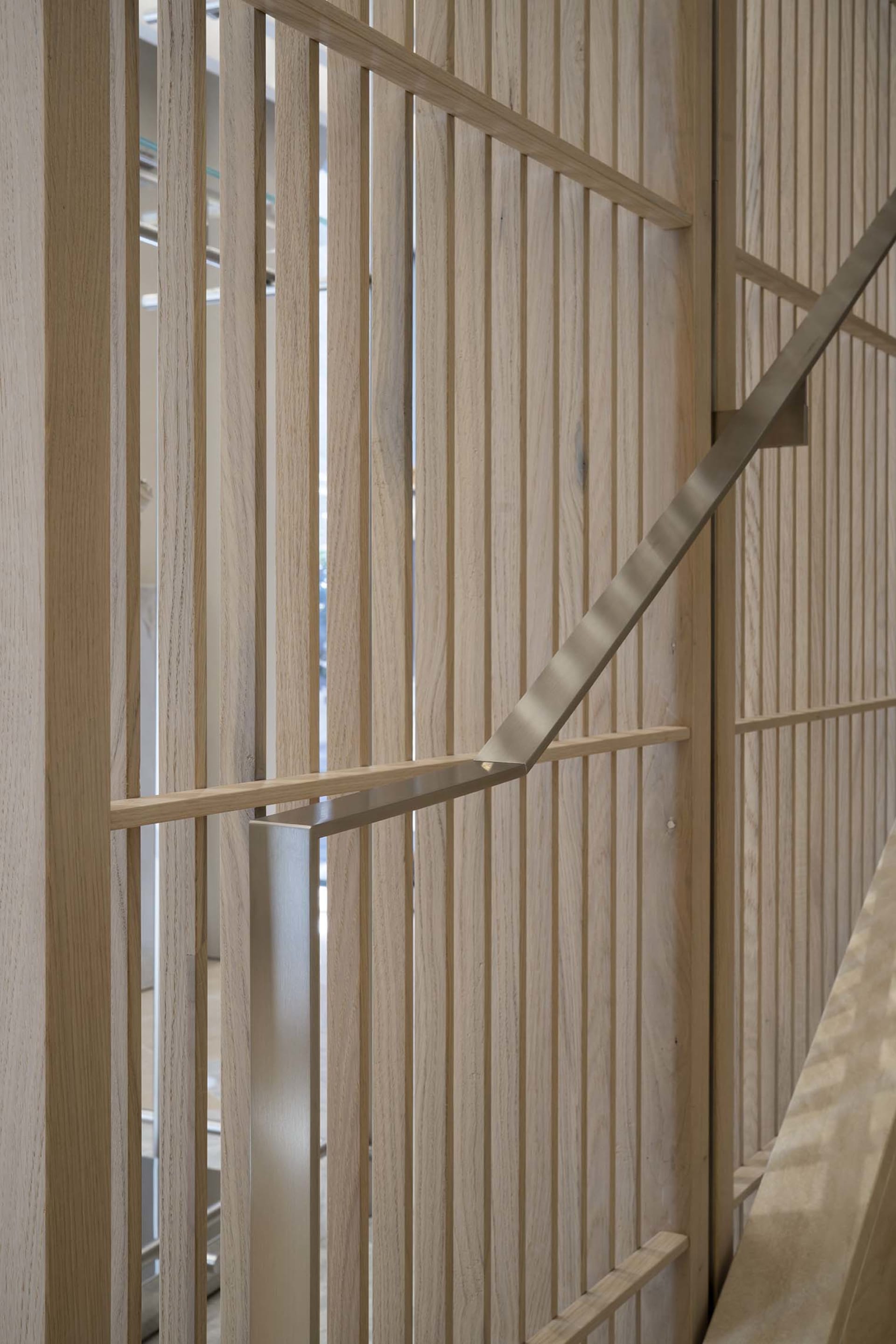 Modern staircase with wooden vertical panels and metal handrails.
