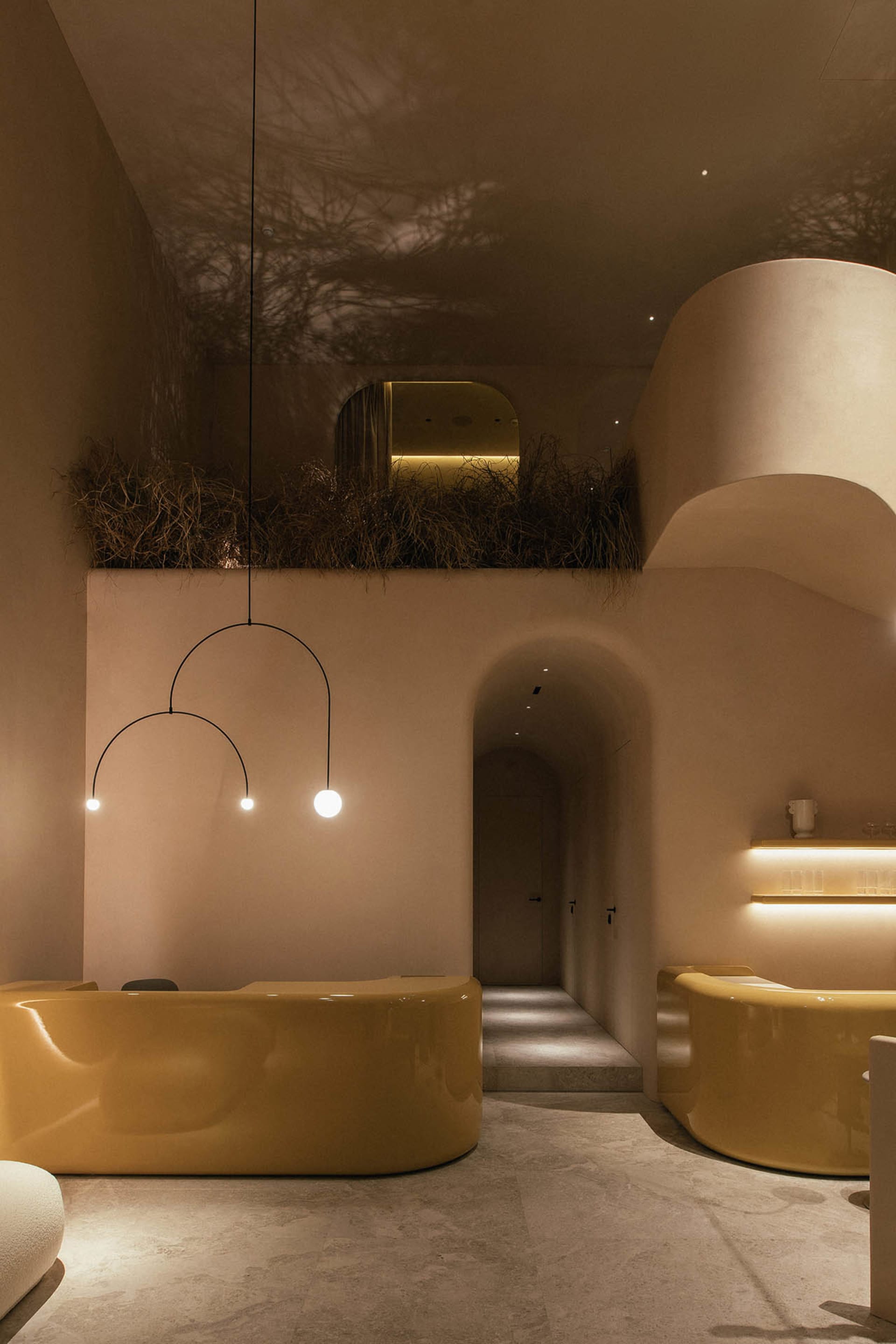 Interior shot of a modern spa with concrete finishes, curved yellow seating, and minimalist lighting.