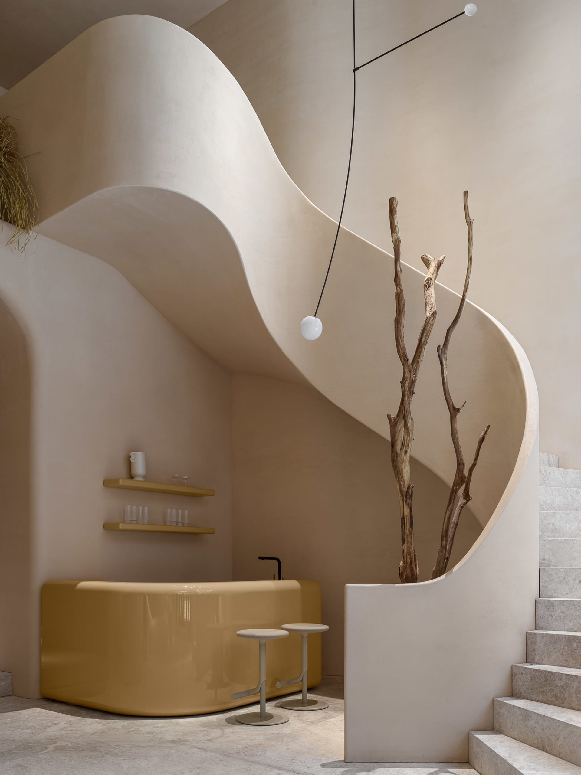A minimalist bar area with a yellow bar counter, concrete stairs, and a dried plant.