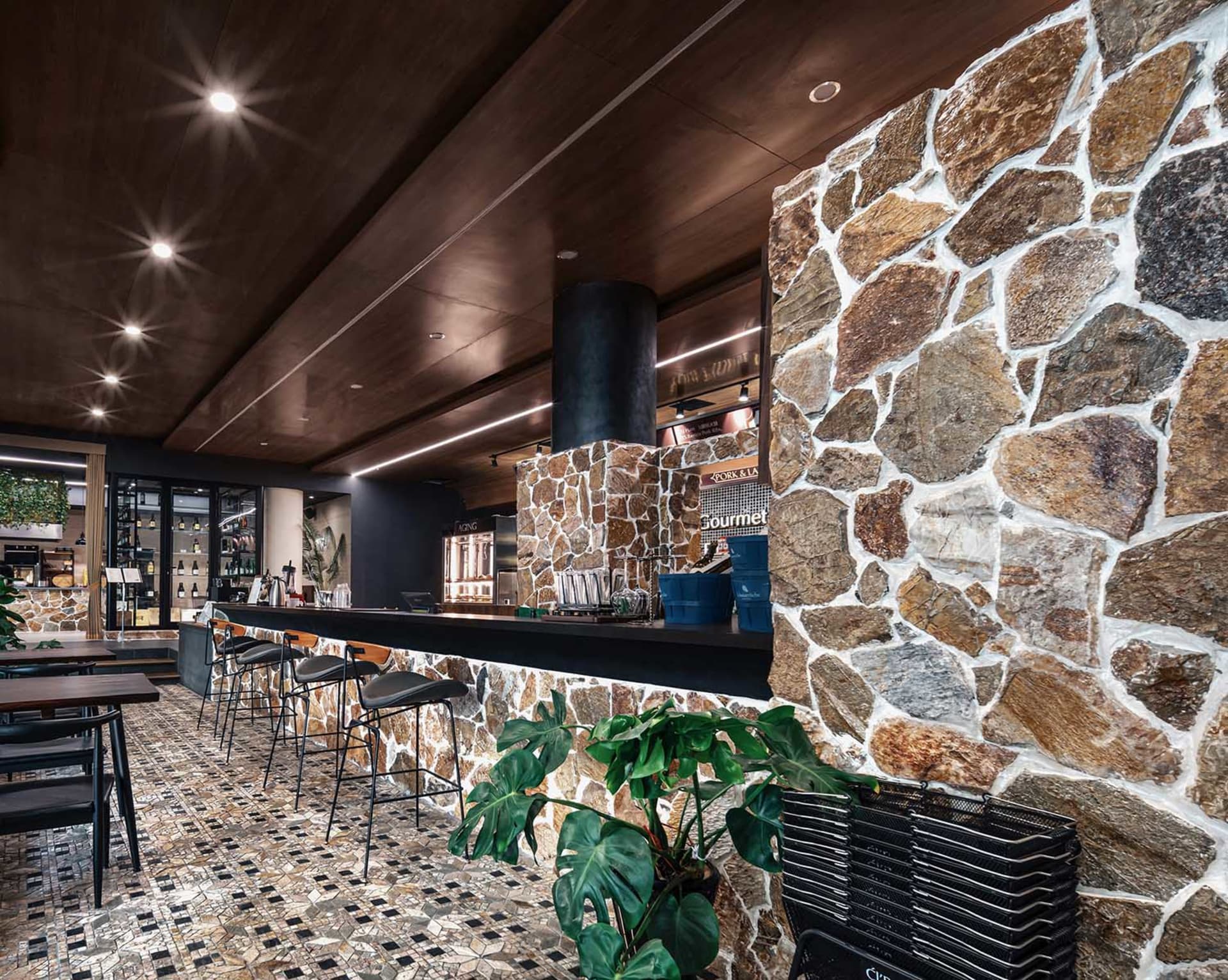 Interior of an industrial-style restaurant featuring a stone bar counter and tiled flooring.