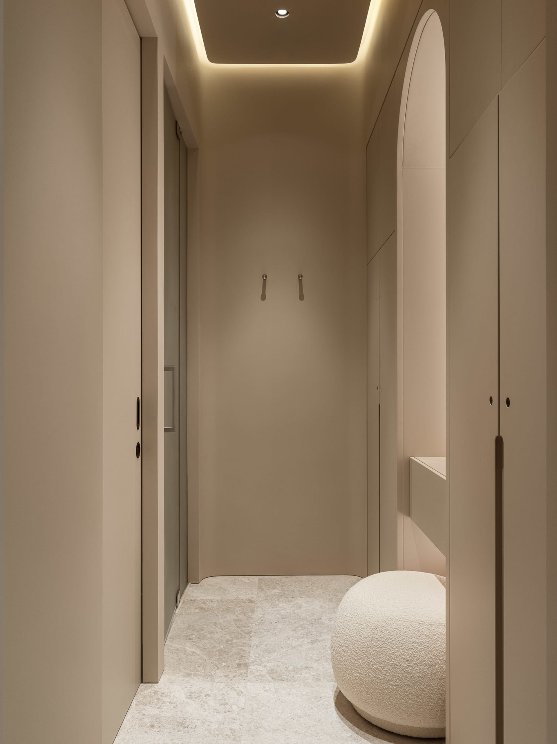 Minimalist corner wardrobe with neutral-toned materials and a cushioned seat.