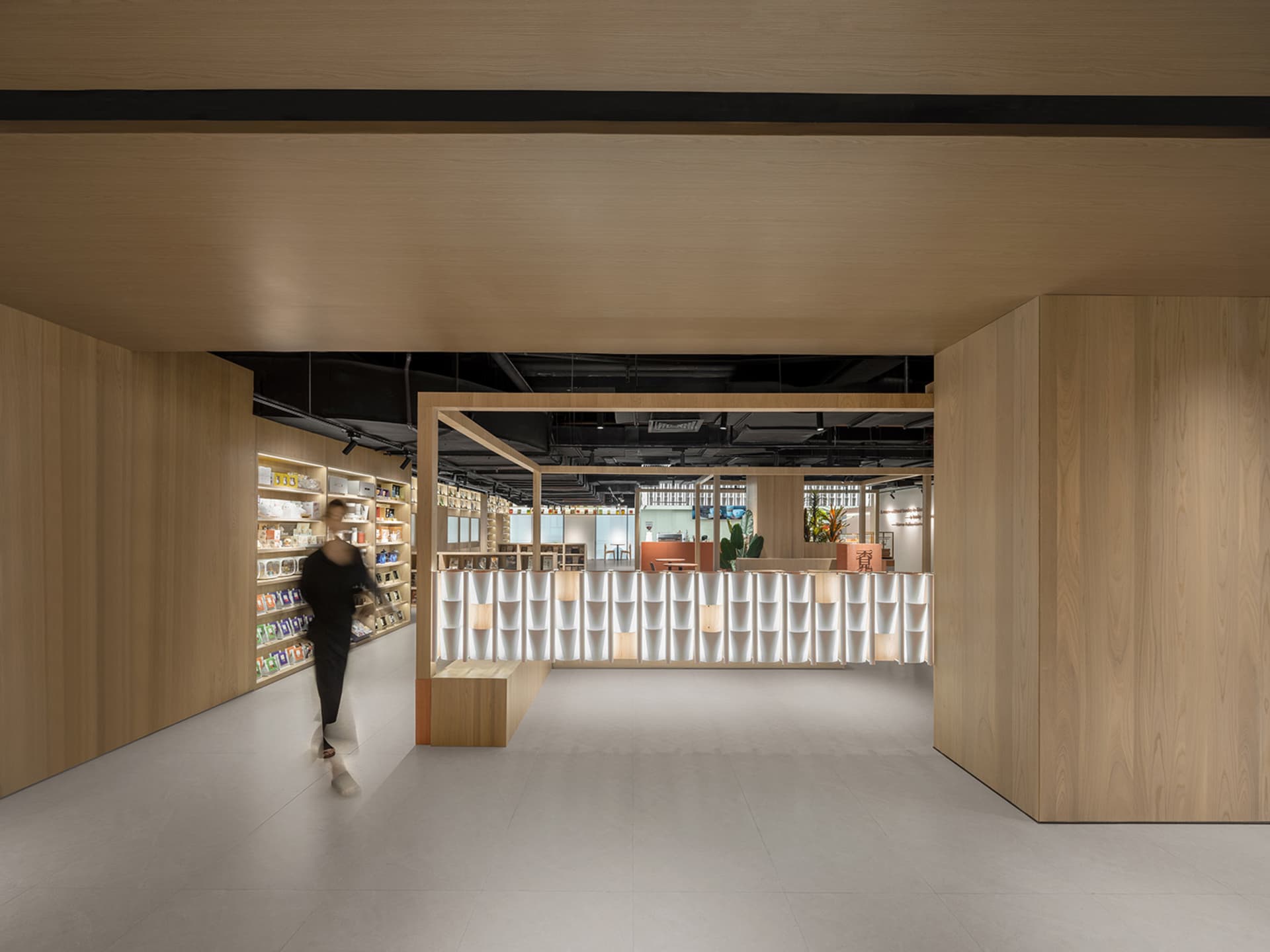 Modern coffee shop interior with wooden finishes, illuminated display cases, and minimalist design.