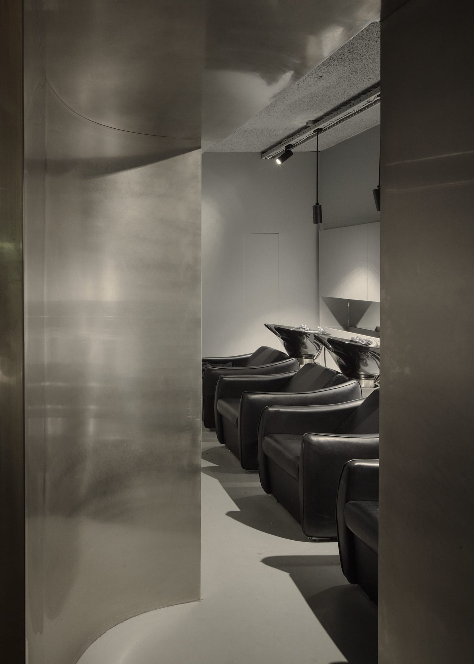 Modern industrial-style salon interior with metallic finish and sleek, minimalist seating.