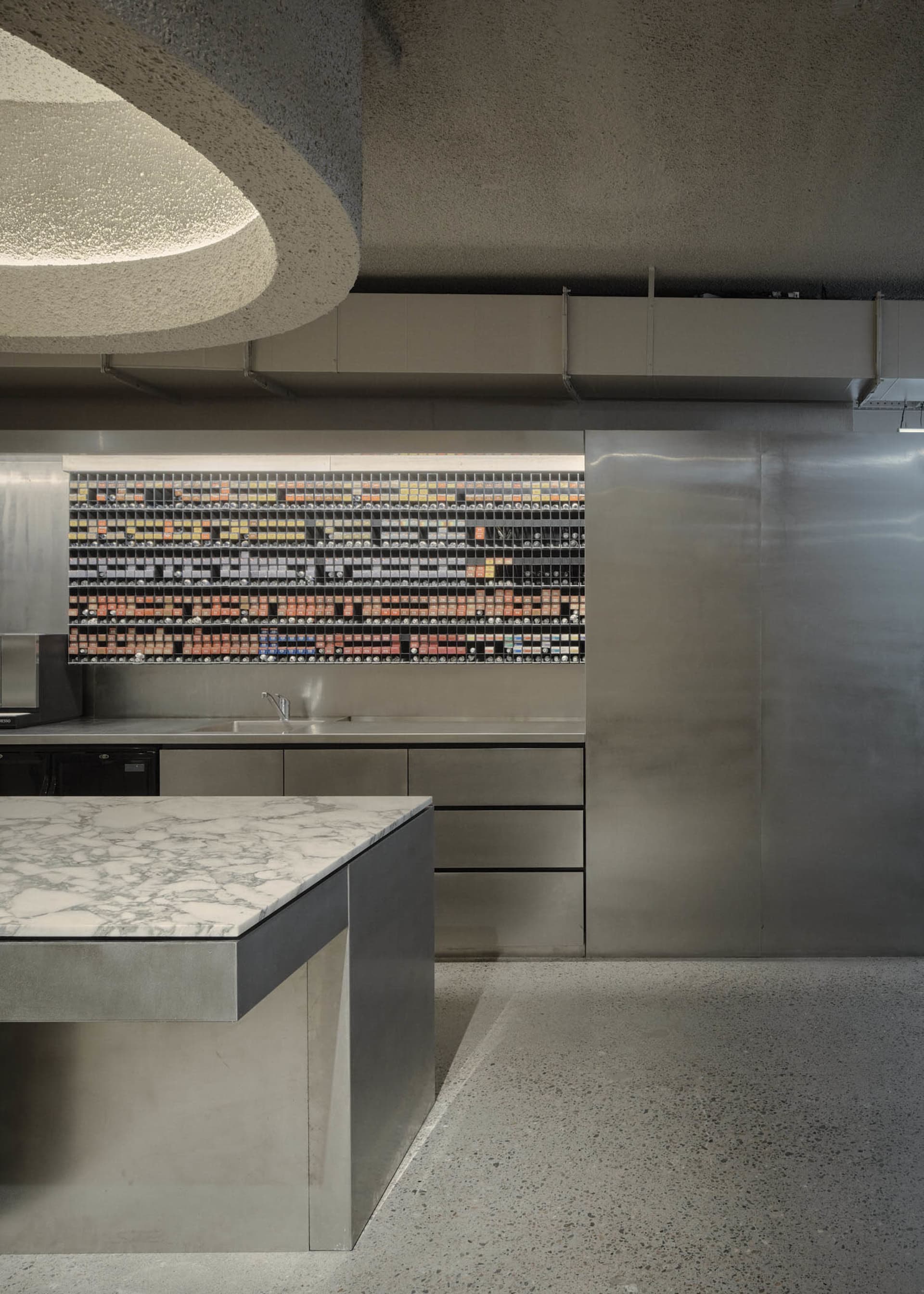 A sleek, modern commercial kitchen featuring steel appliances, marble countertops, and a minimalist design.