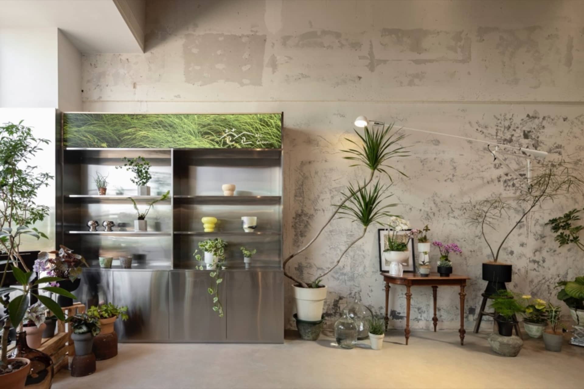 Modern plant shop featuring metal planters and concrete walls.