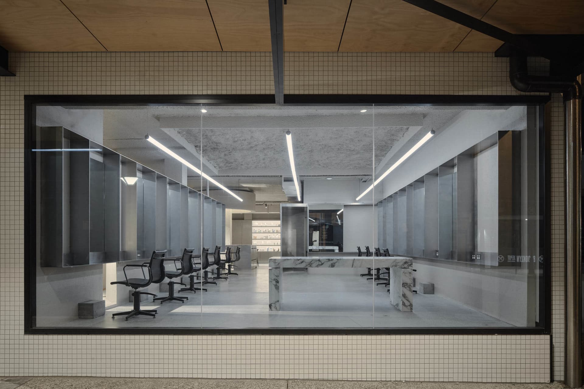 Modern salon interior featuring white marble countertops and chairs, with a minimalist design aesthetic.