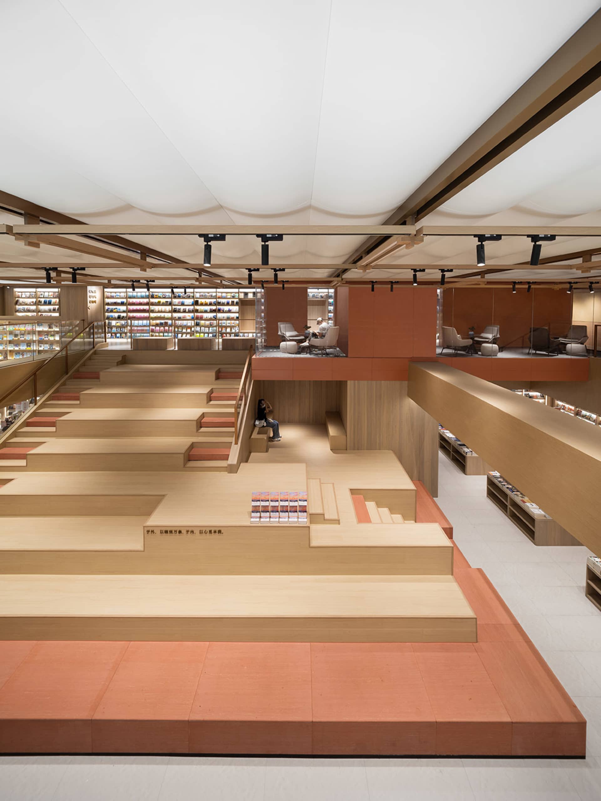 A modern bookstore with a multi-level wood floor plan and open shelves.