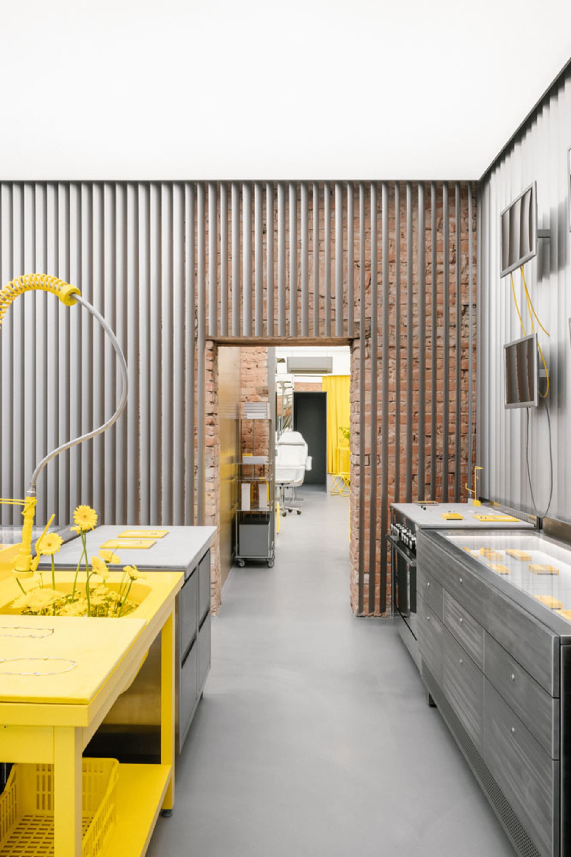 A modern kitchen with grey concrete walls and yellow countertops.