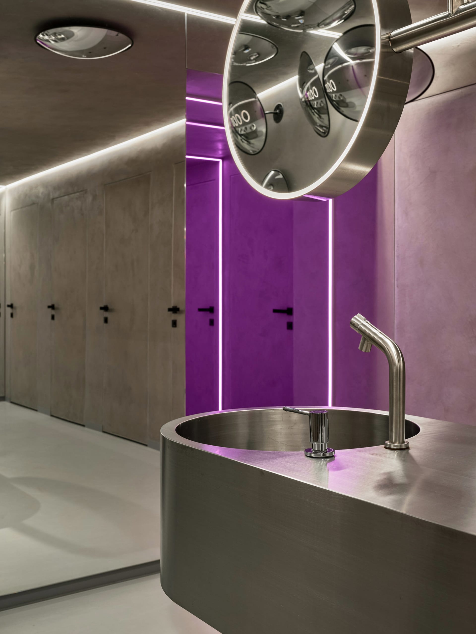 A modern bathroom with a metal sink and purple accents