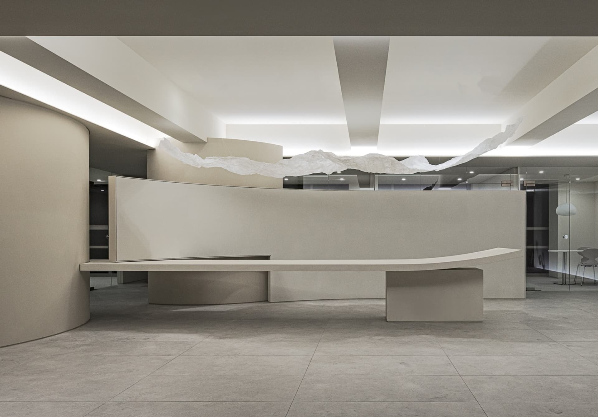 A modern corporate reception area with curved concrete surfaces and white lighting.