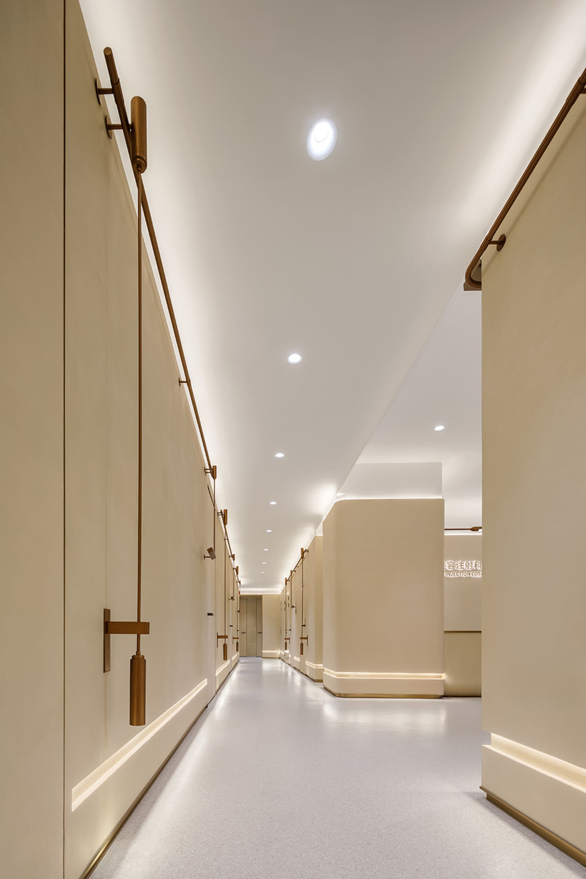 A modern, white-painted corridor featuring brass handrails and minimalist design.