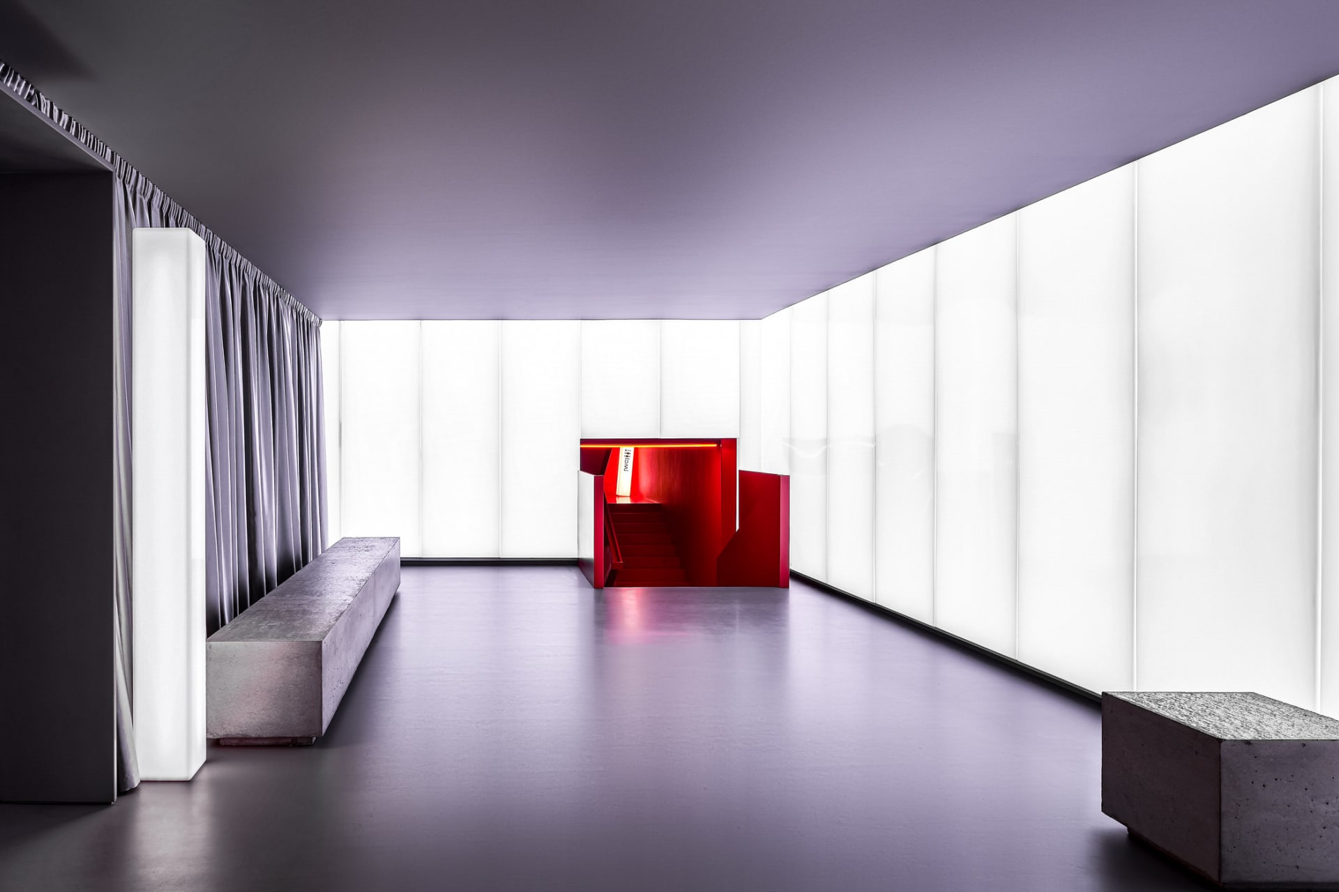 Modern entryway featuring sleek, minimalist design with red accents on staircase and walls, complemented by concrete flooring