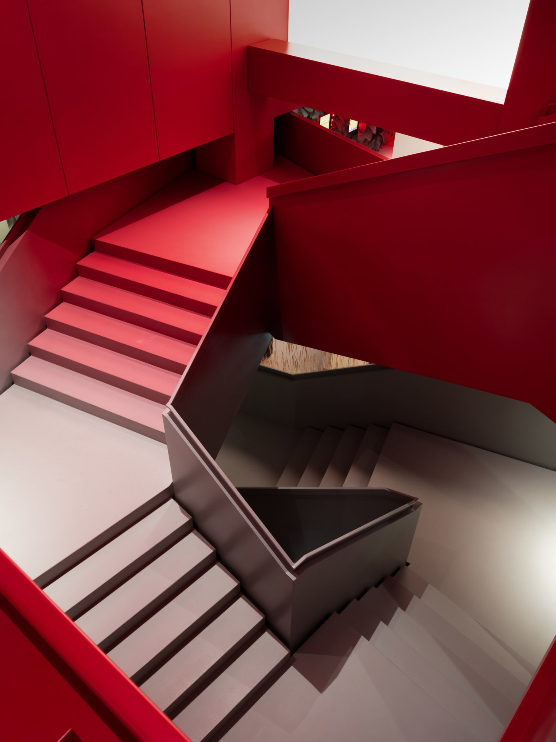 Staircase featuring modern design with red tiles and white walls.
