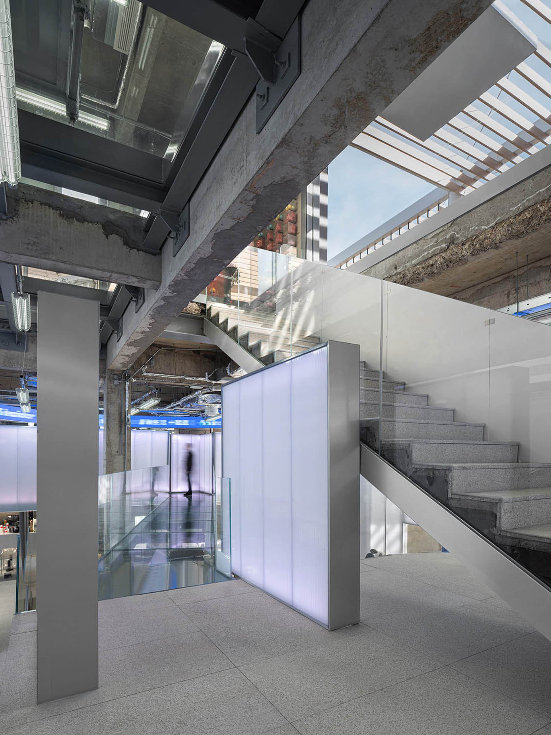 A modern industrial staircase made of concrete with glass railings and a glass partition.