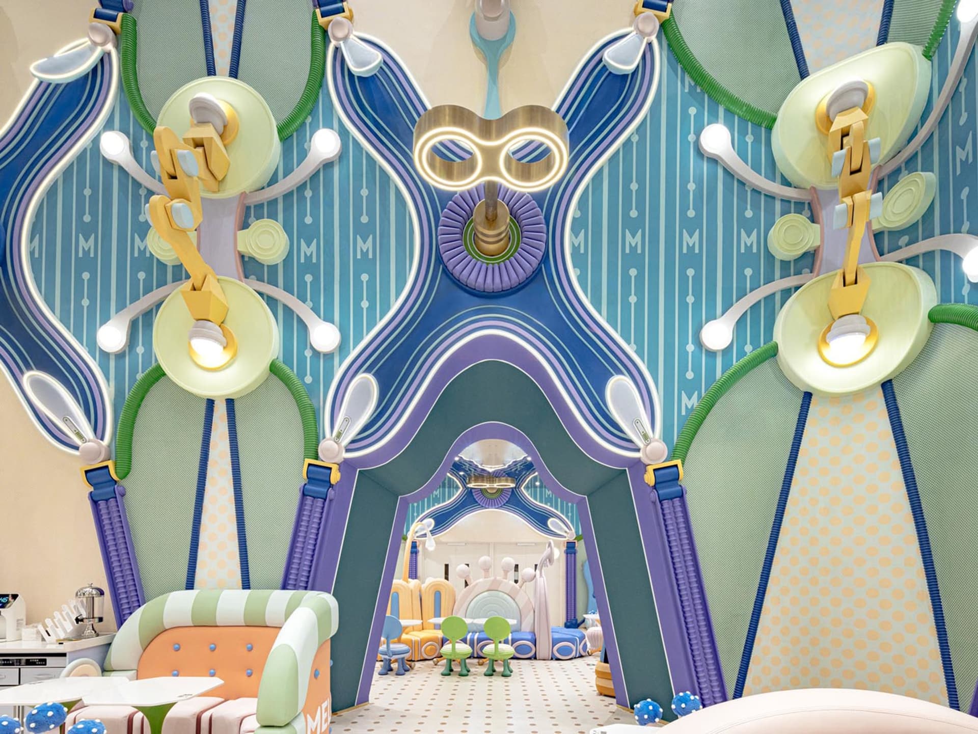 A vibrant, modern playroom with colorful plastic toys, wooden furniture, and fabric seating.