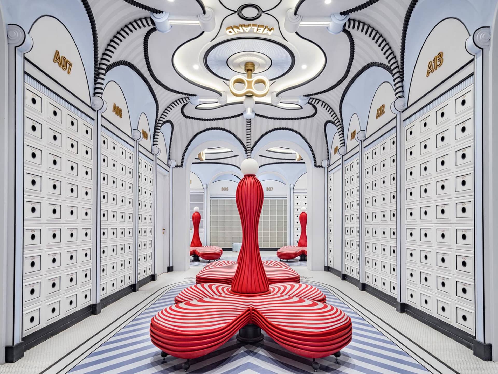 Modern retail store interior with concrete walls, white and red striped seating areas, and archways with names above them.