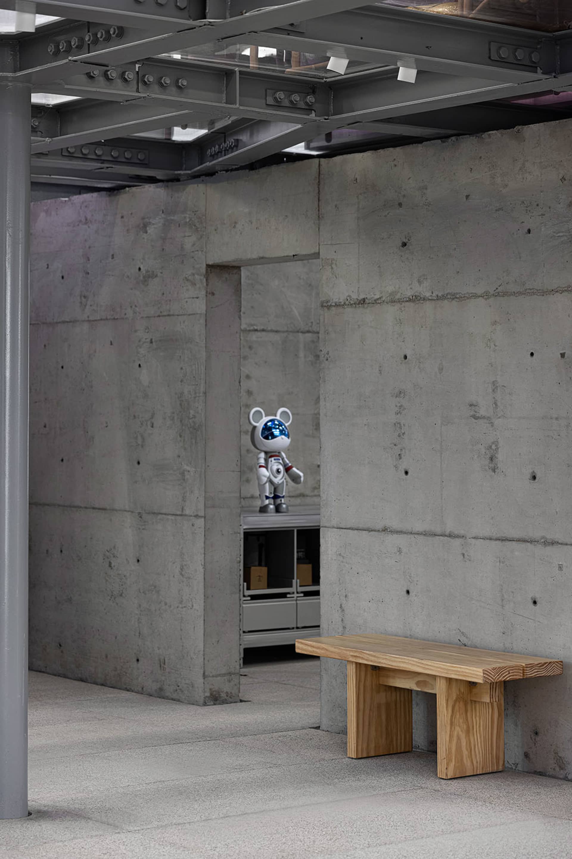 Modern industrial interior with minimalist design, featuring a concrete wall and metal beams.